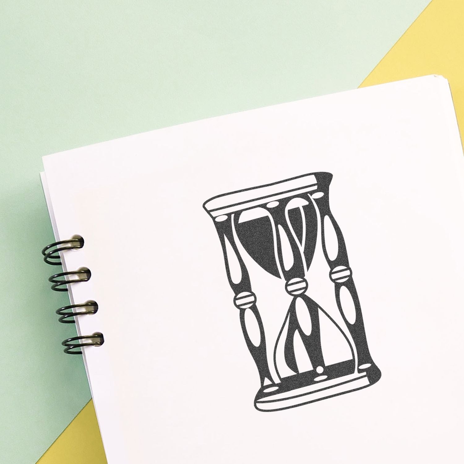Spiral notebook with hourglass illustration on white paper, symbolizing time management and productivity.