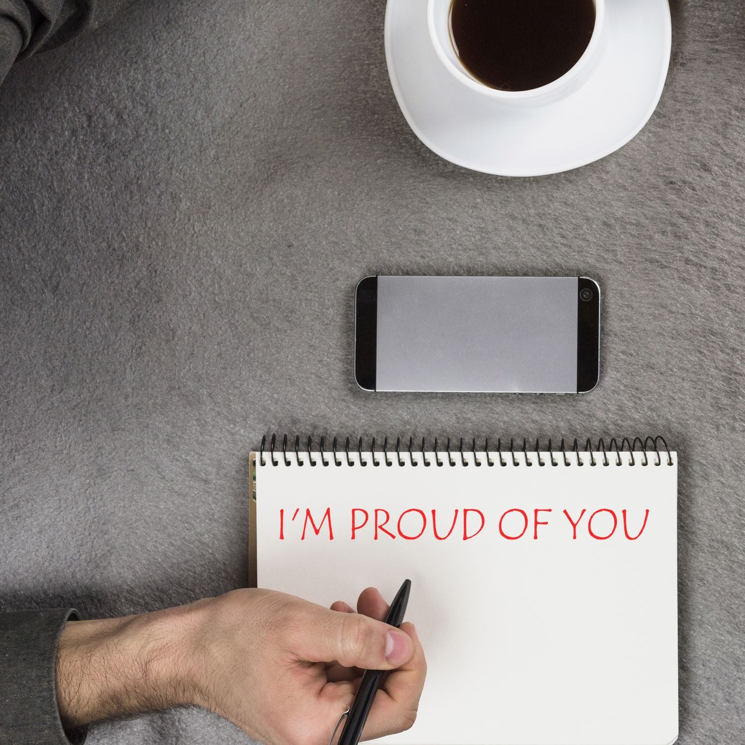 Man writes a motivational message Im proud of you in a notebook with coffee in backgroundencouragement and appreciation.