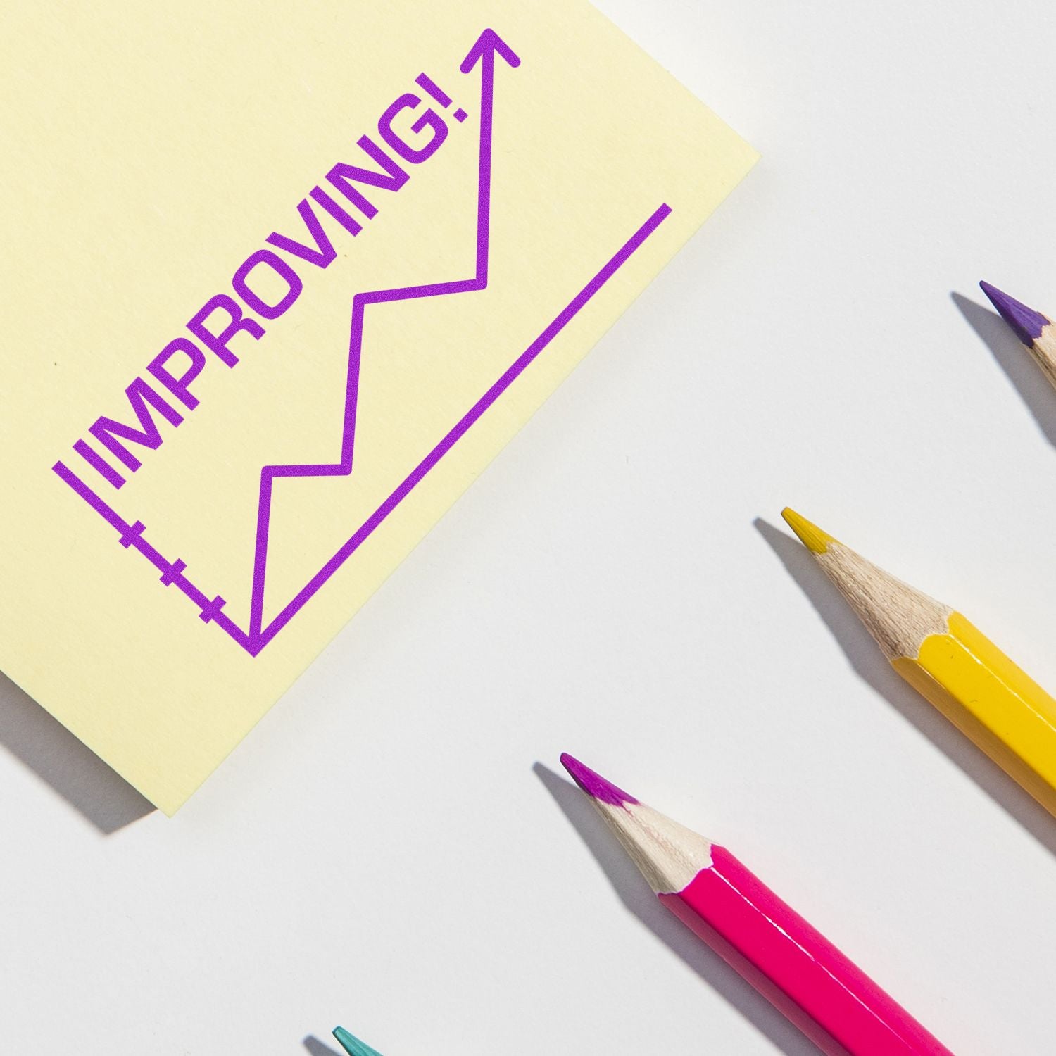 Improving growth concept with upward arrow chart on sticky note and colored pencils on white background