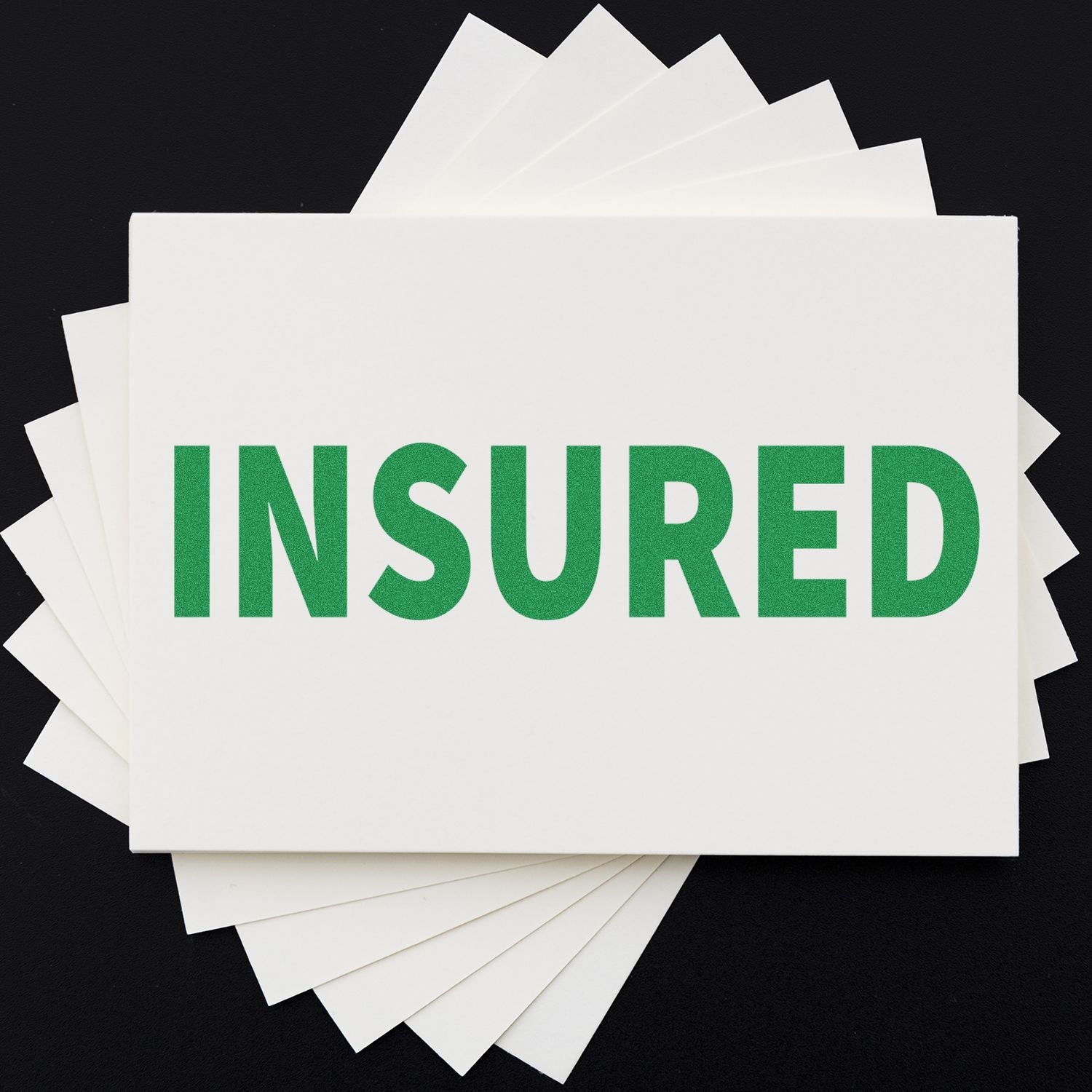 Stack of insurance cards displaying INSURED in green, representing insurance coverage and policy protection.