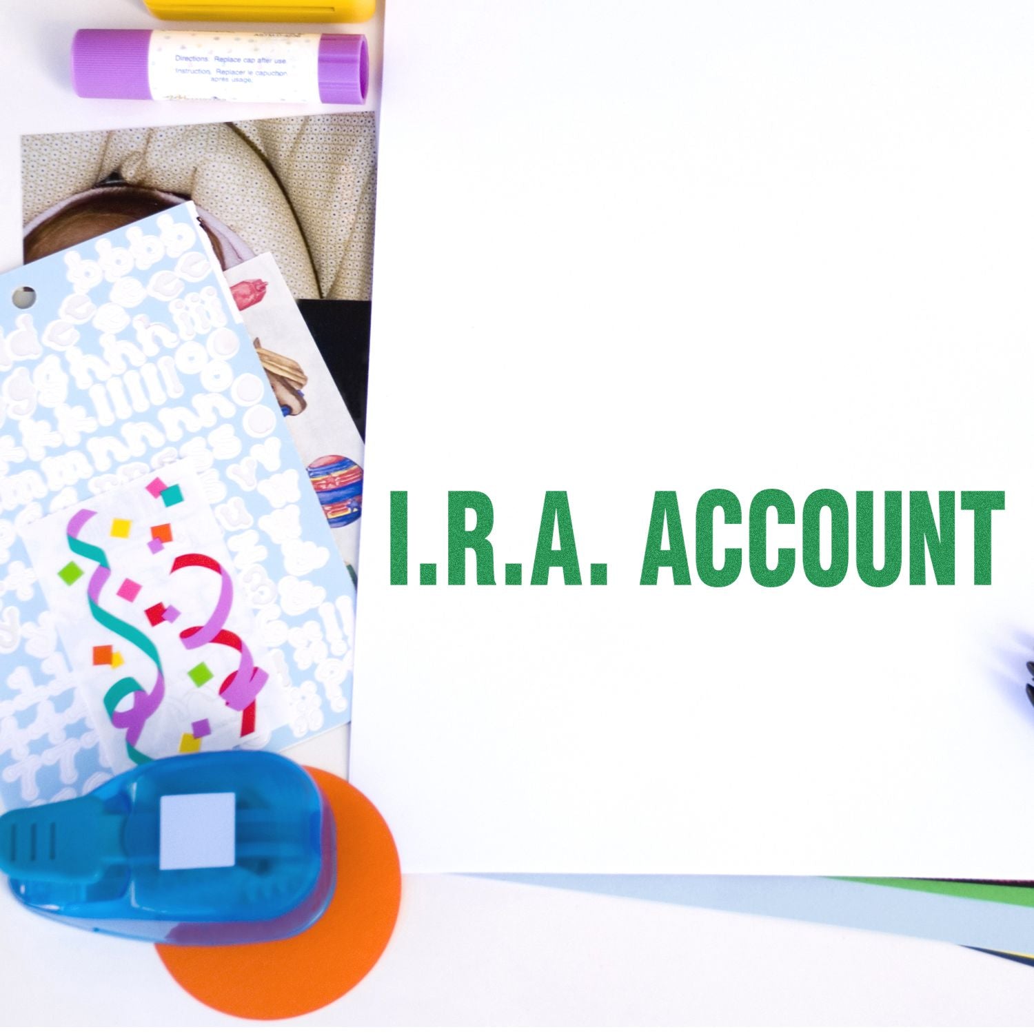 Colorful art supplies and paper crafts beside a blank sheet labeled I.R.A. Account on a white background.