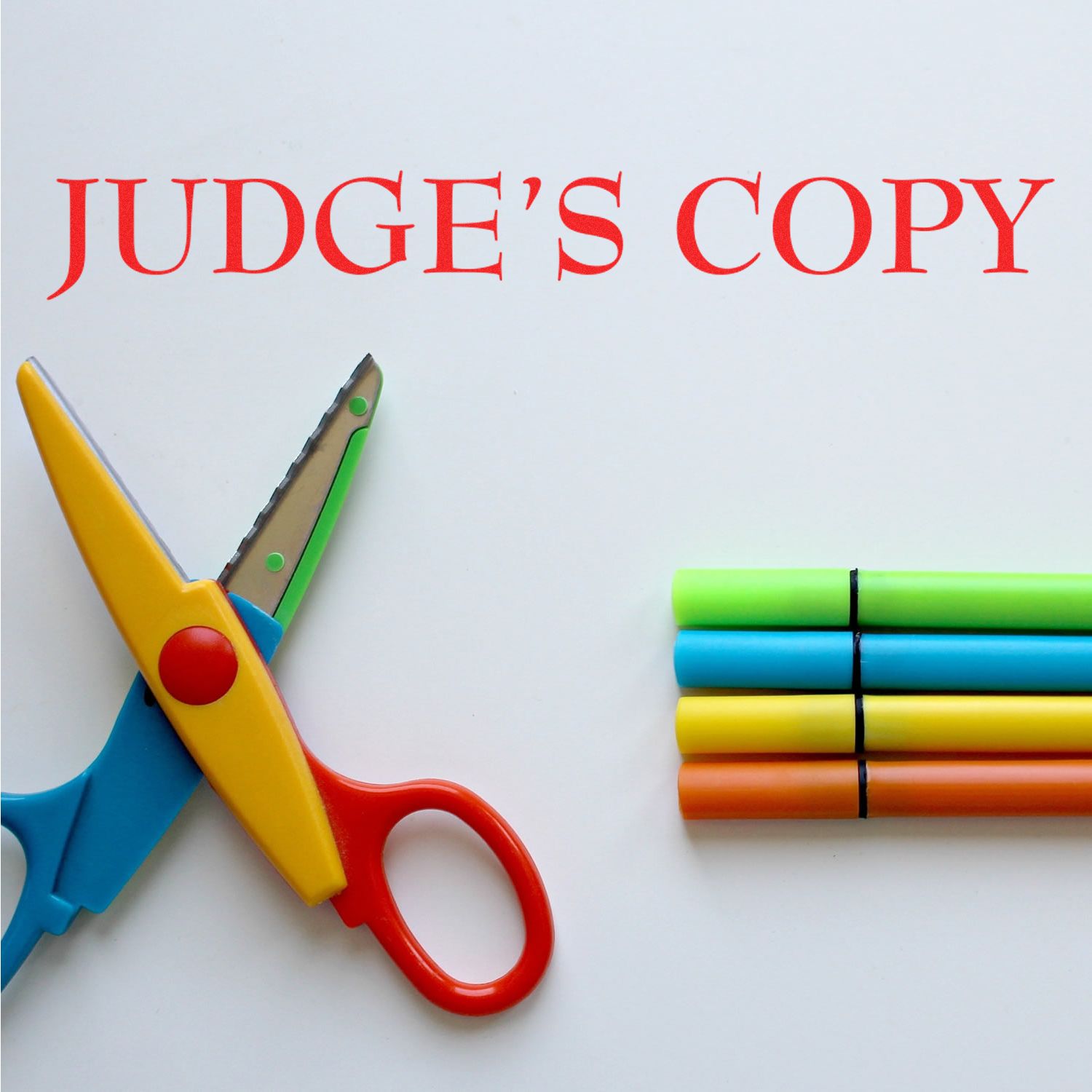 Judges Copy label over scissors and colored pencils, showing an edited version for school projects or document review.