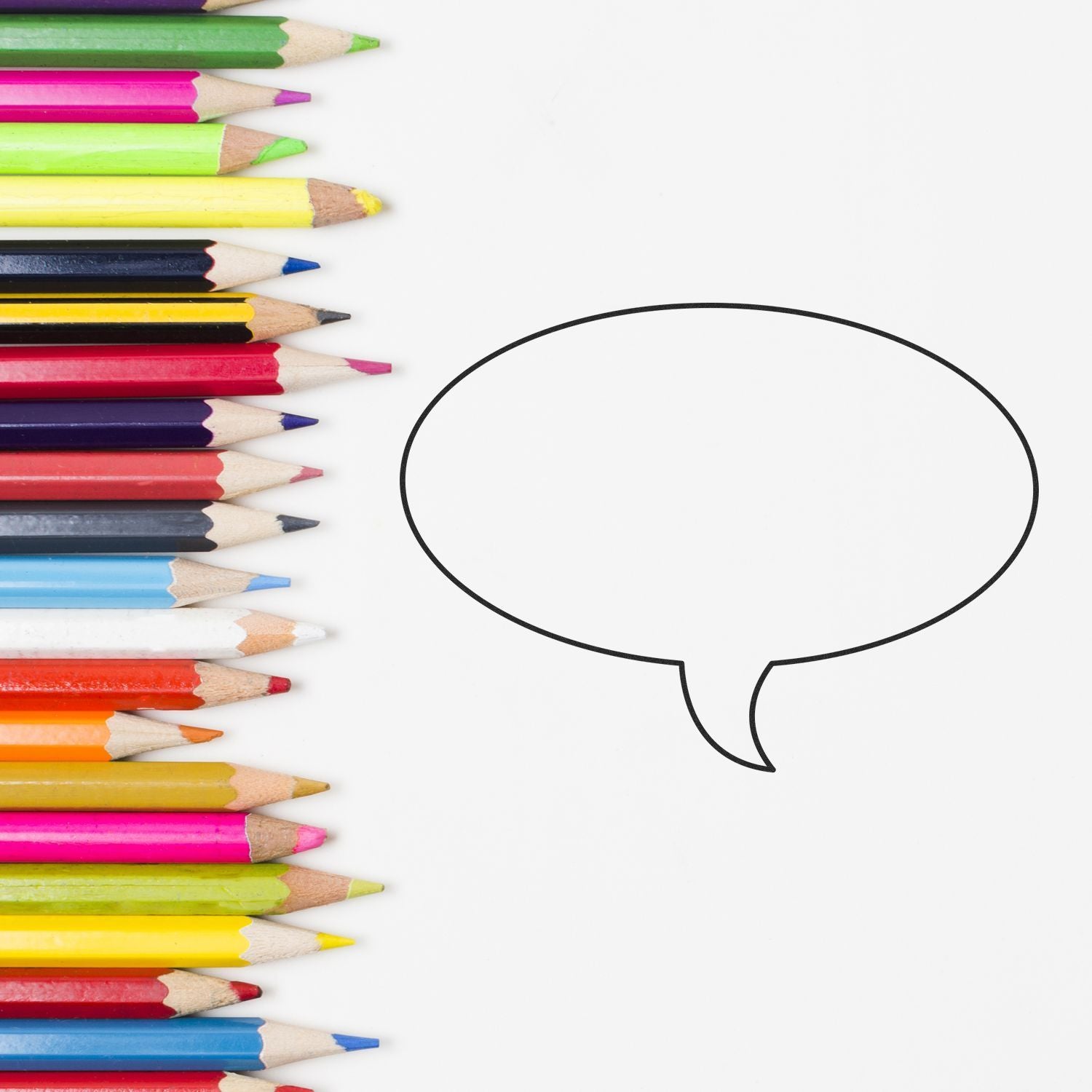 Colorful pencils lined up beside empty speech bubble on white background, creative education concept.