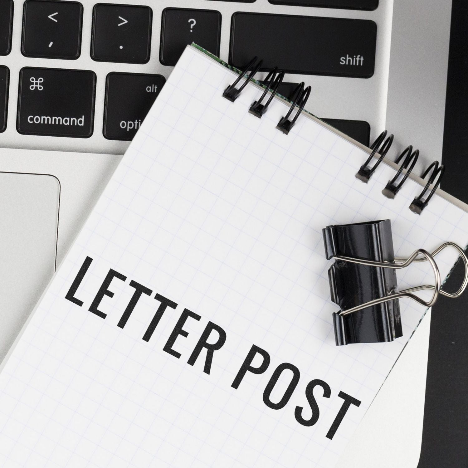 Notebook page labeled LETTER PURPOSE with binder clips and computer keyboard, illustrating writing a letter purpose statement.