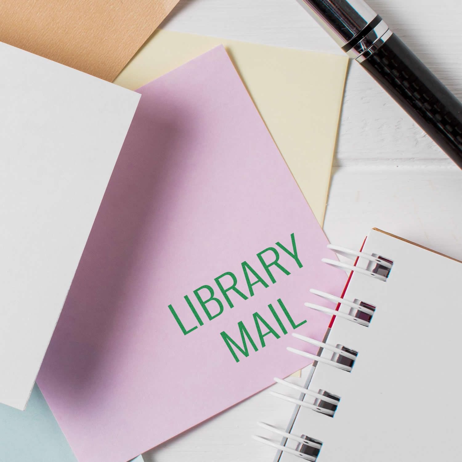 Planner notebook page labeled LIBRARY MAIL with colorful paper and pen, helping organize library mail shipments and tracking.