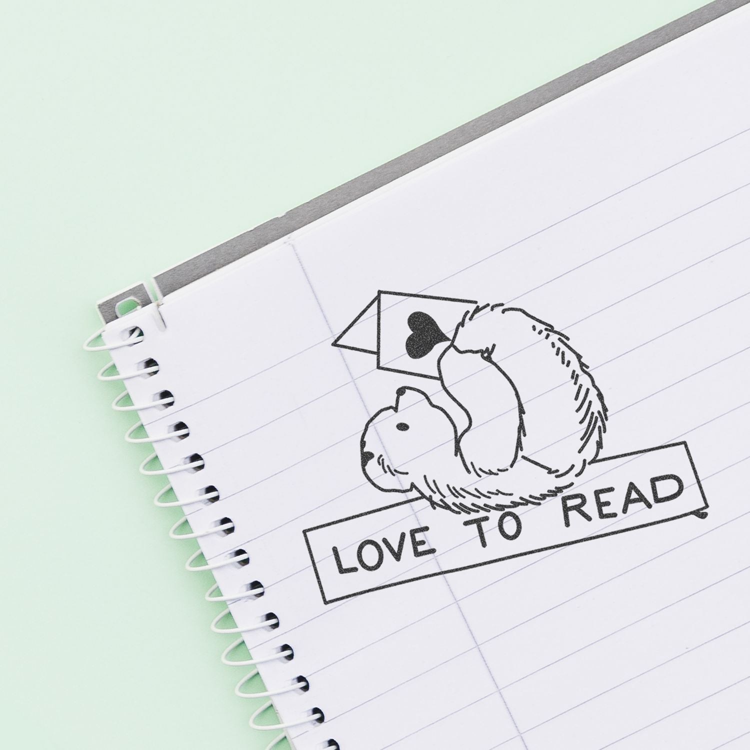 Spiral notebook with Love to Read stamp and cute bear reading a book on a pastel background.