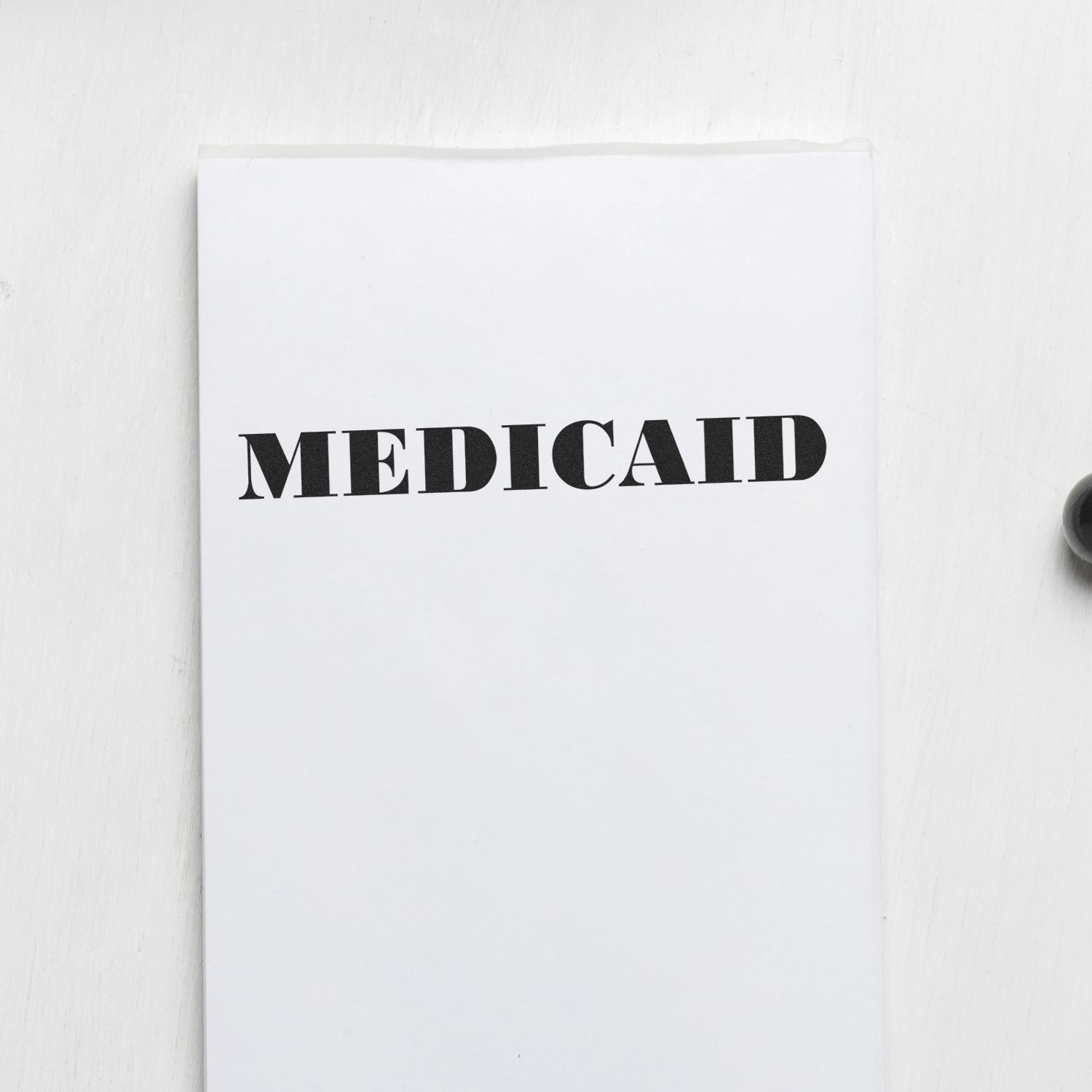 White folder labeled Medicaid on a white background, representing Medicaid healthcare benefits and assistance document.