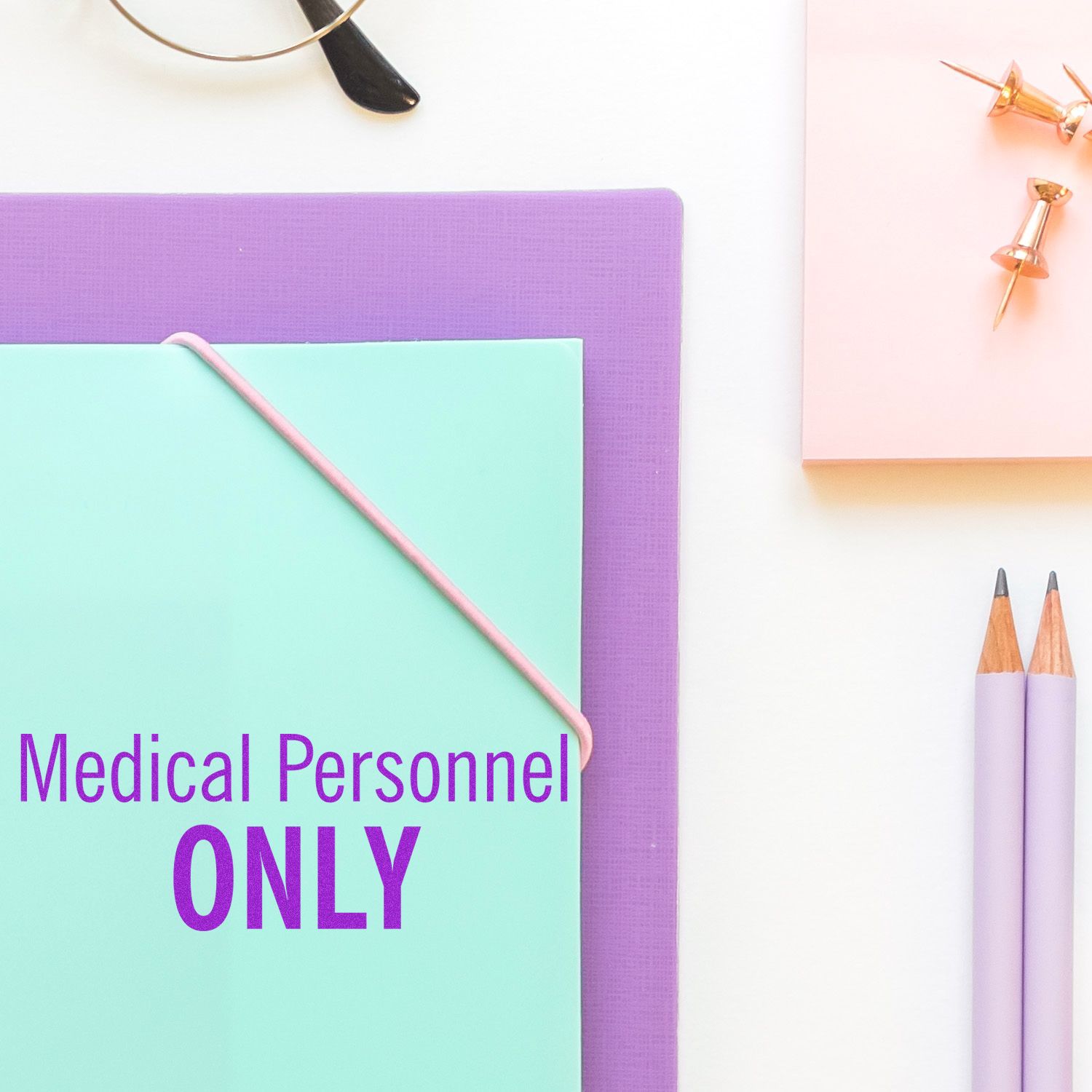Pastel office stationery with Medical Personnel Only sign, pencils, and push pins on a clean white background.