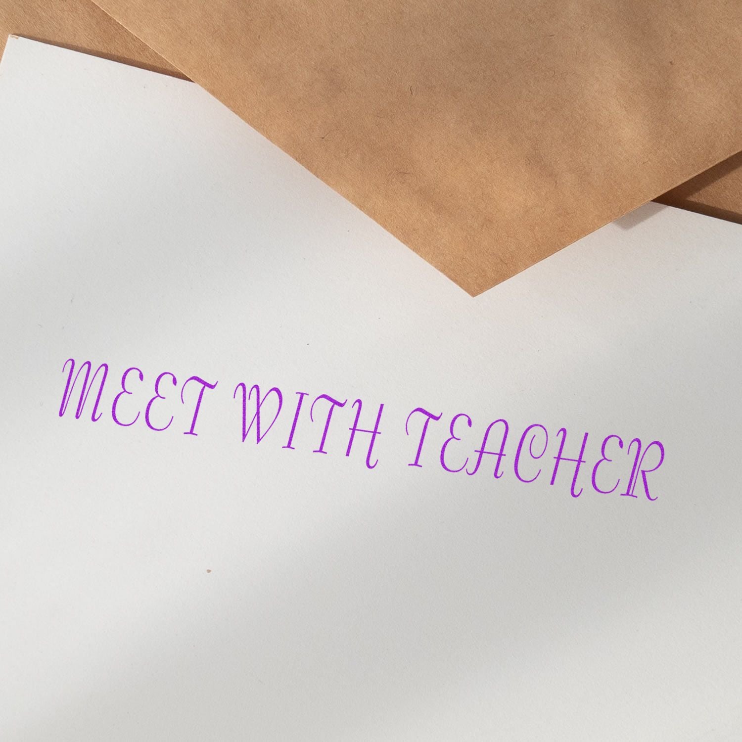 Handwritten purple note on white paper reading Meet with Teacher, with kraft envelope corner for school meeting reminder context.