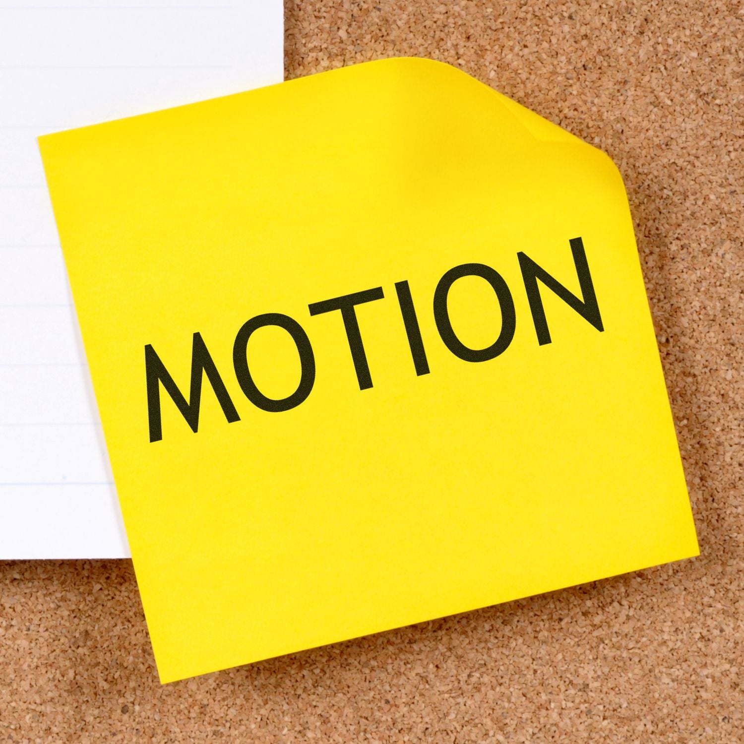 Yellow sticky note on cork board with the word MOTION, symbolizing movement and motion concepts for marketing or education.