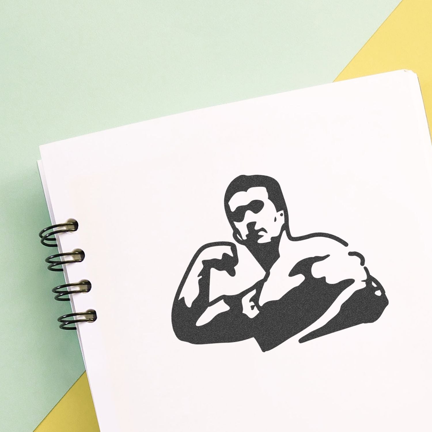 Minimalist notebook with black stencil portrait of a muscular man on pastel background