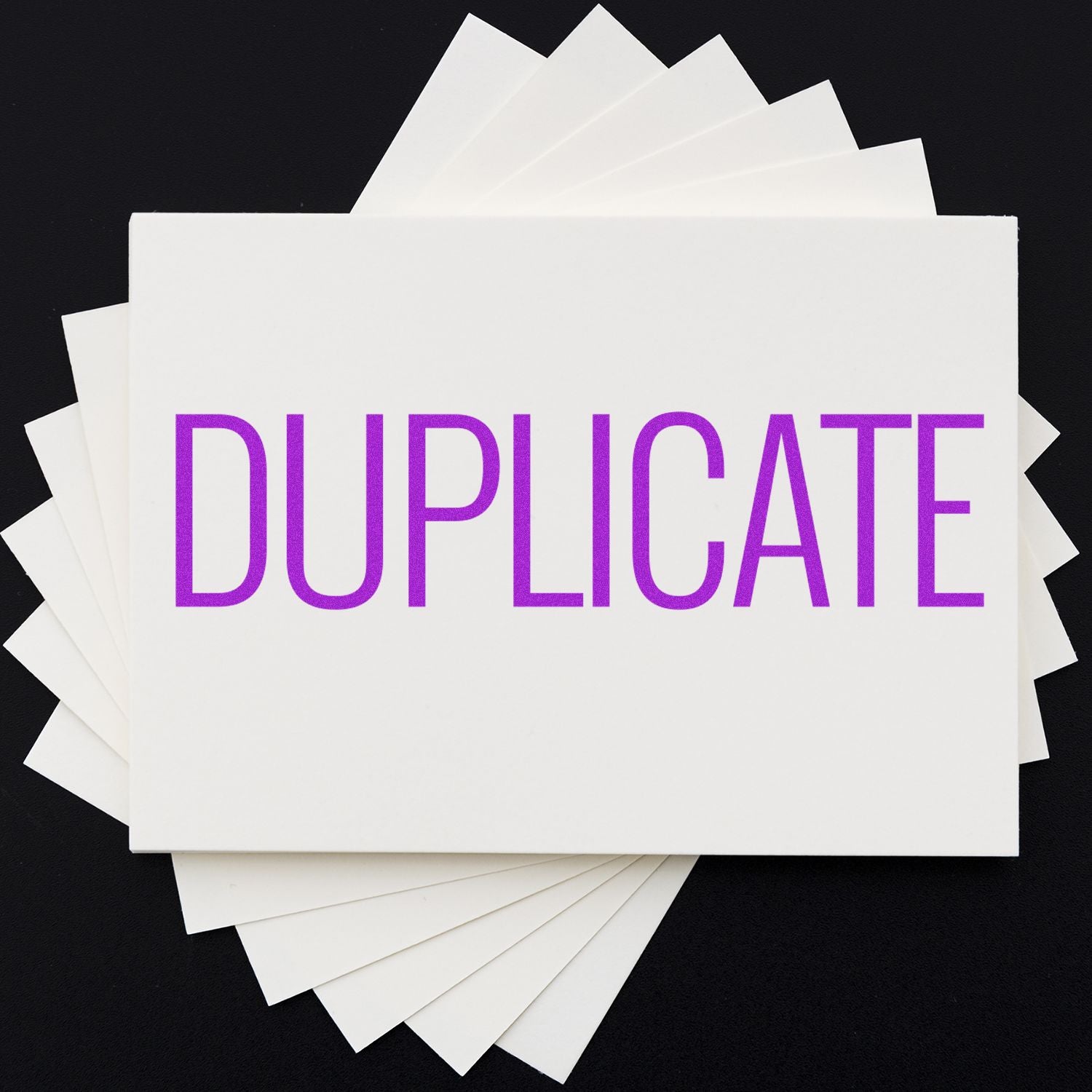 Stack of duplicate cards showing the word DUPLICATE in purple, representing document duplication and copy creation on a dark background.