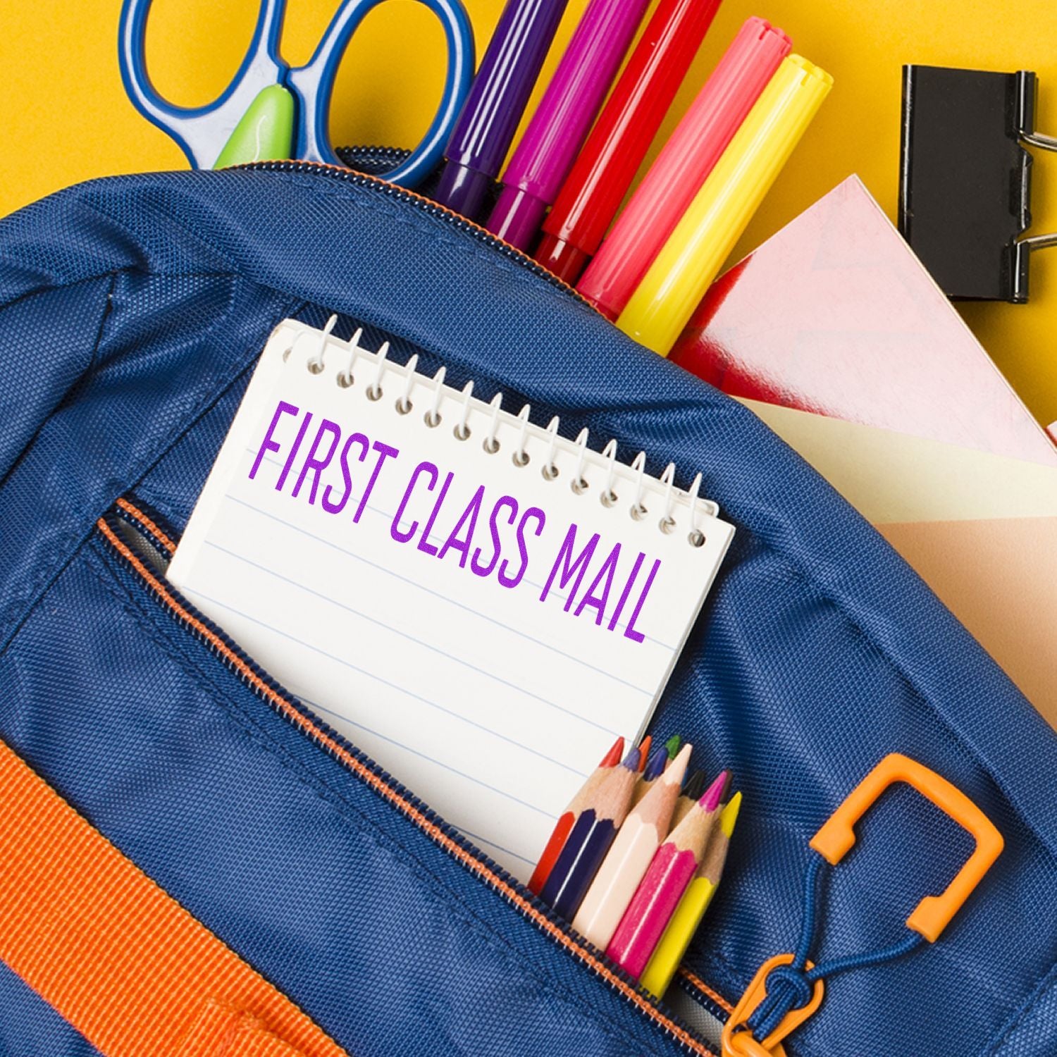 Blue pencil case with colorful markers and a notebook reading First Class Mailback-to-school stationery shipping concept.