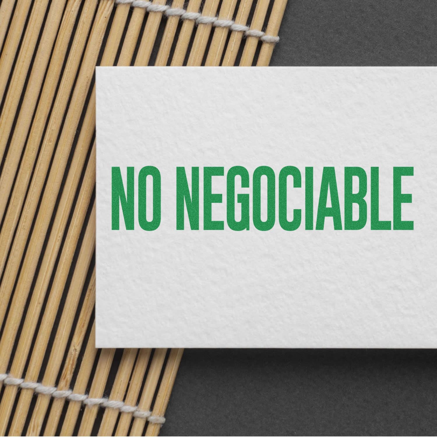 Spanish sign NO NEGOCIABLE on white card over bamboo placemat, emphasizing a no-negotiation policy.