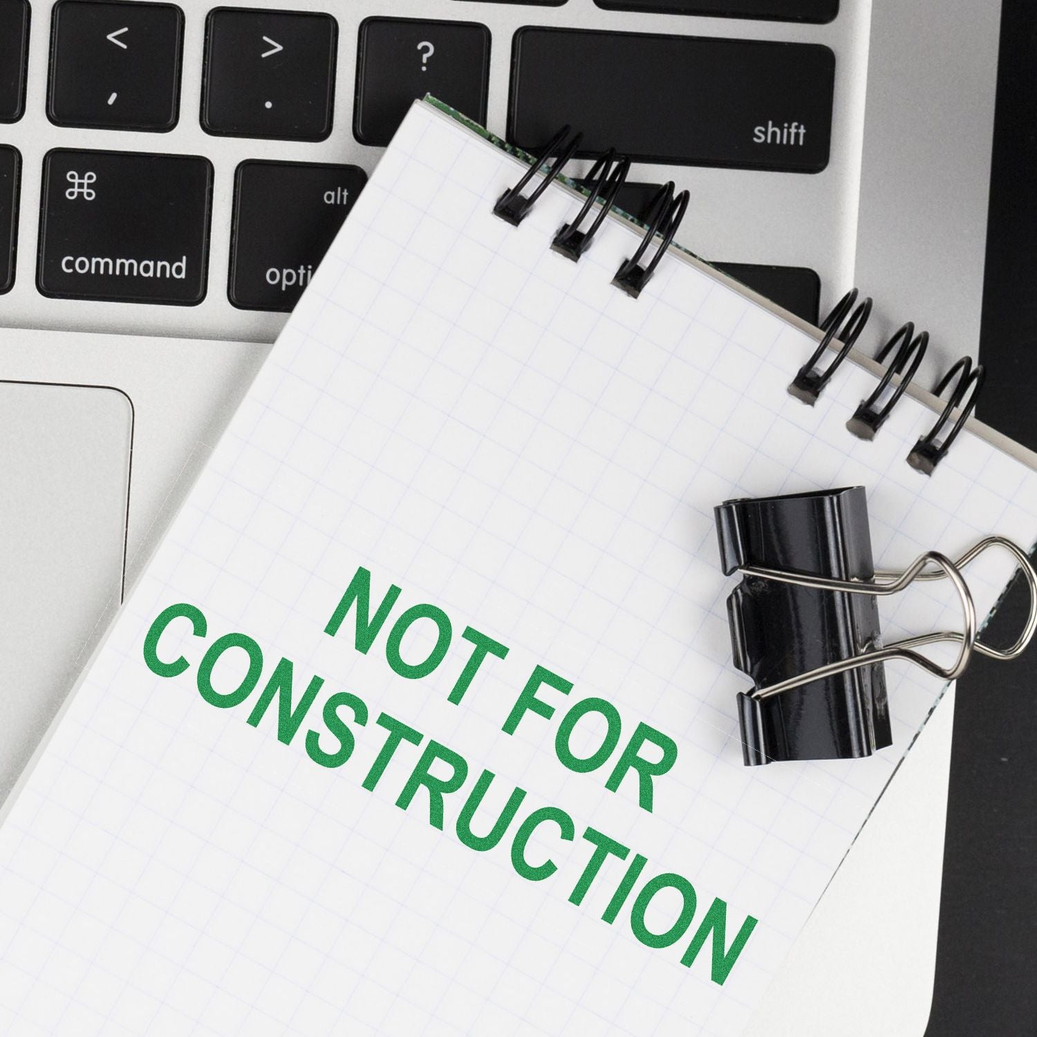 Notebook with Not For Construction text on a laptop keyboard, office planning and design concept.