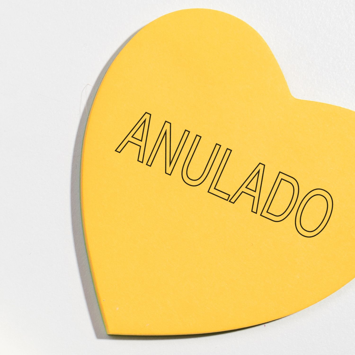 Yellow heart-shaped sign with the word ANULADO in black outlined letters on a white background.