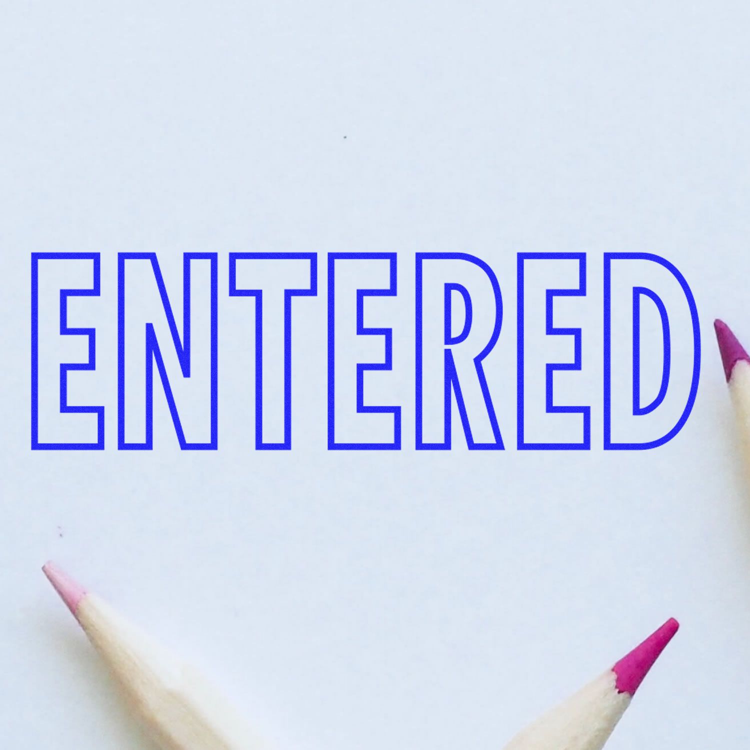 Blue outlined ENTERED text on white paper with colored pencil tips, concept of data entry or confirmation.