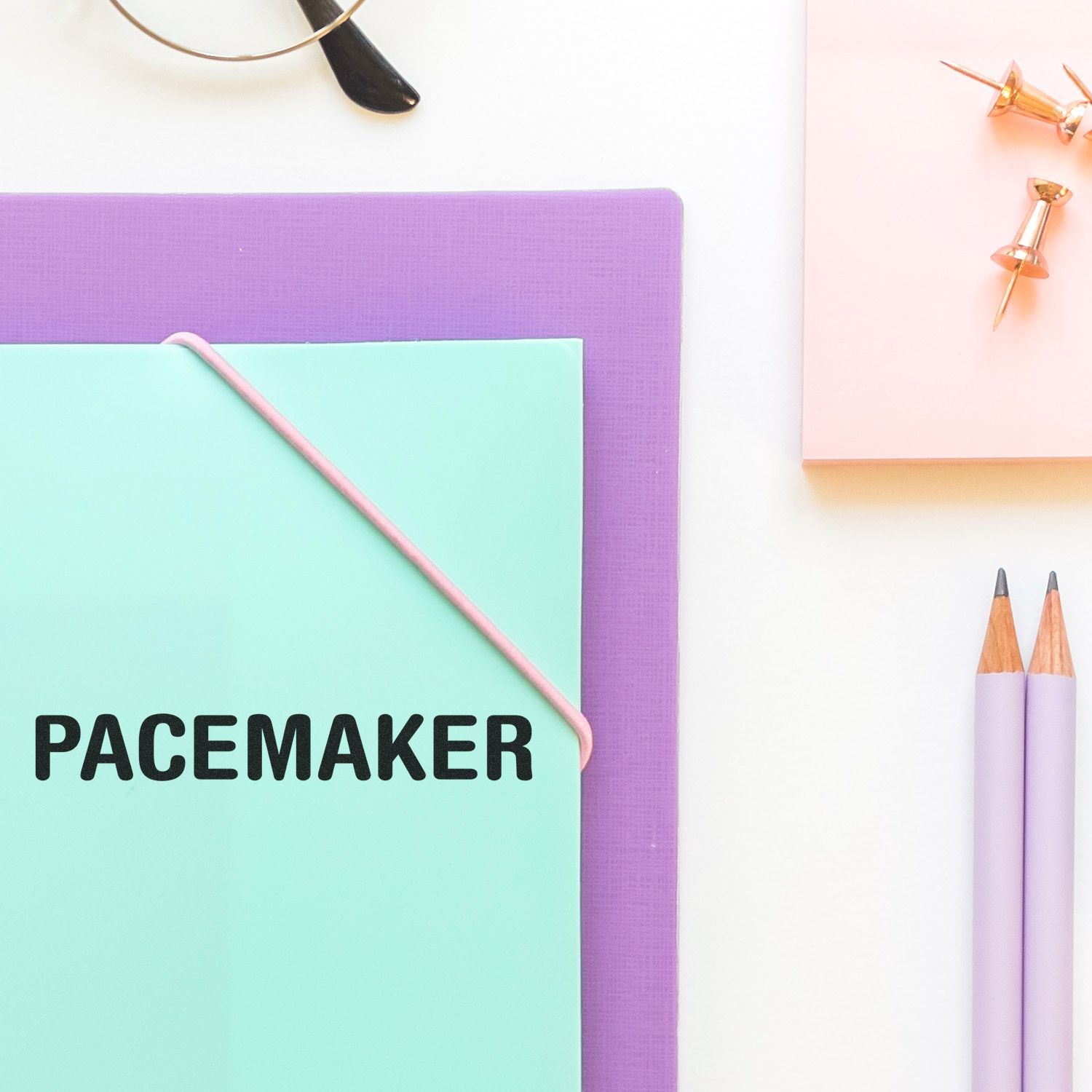 Pastel pacemaker notebook with pencils, push pins, and office stationery on a white background.
