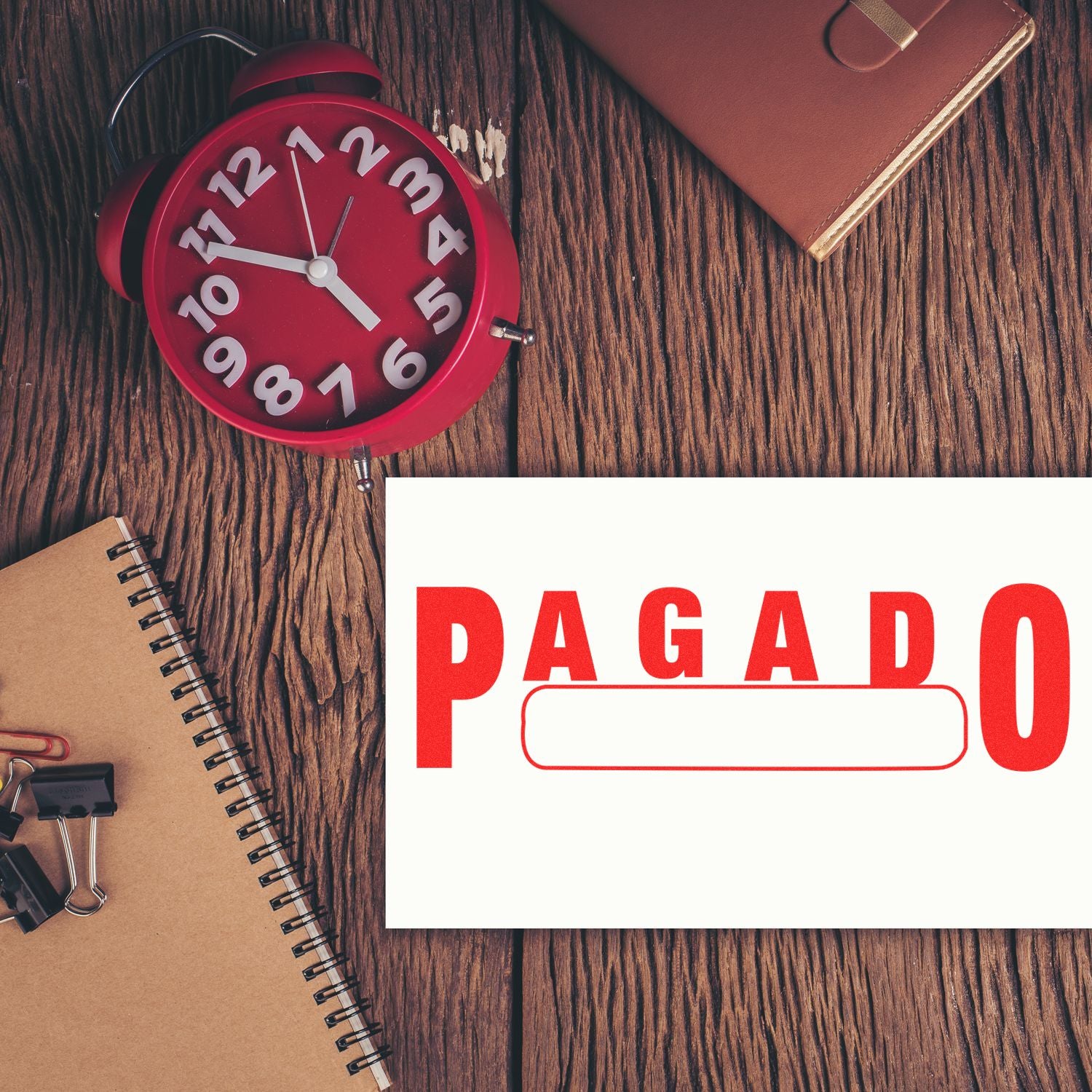 Red alarm clock and notebook on wooden desk with PAGADO stamp, highlighting payment deadline and bill due date urgency for invoices.
