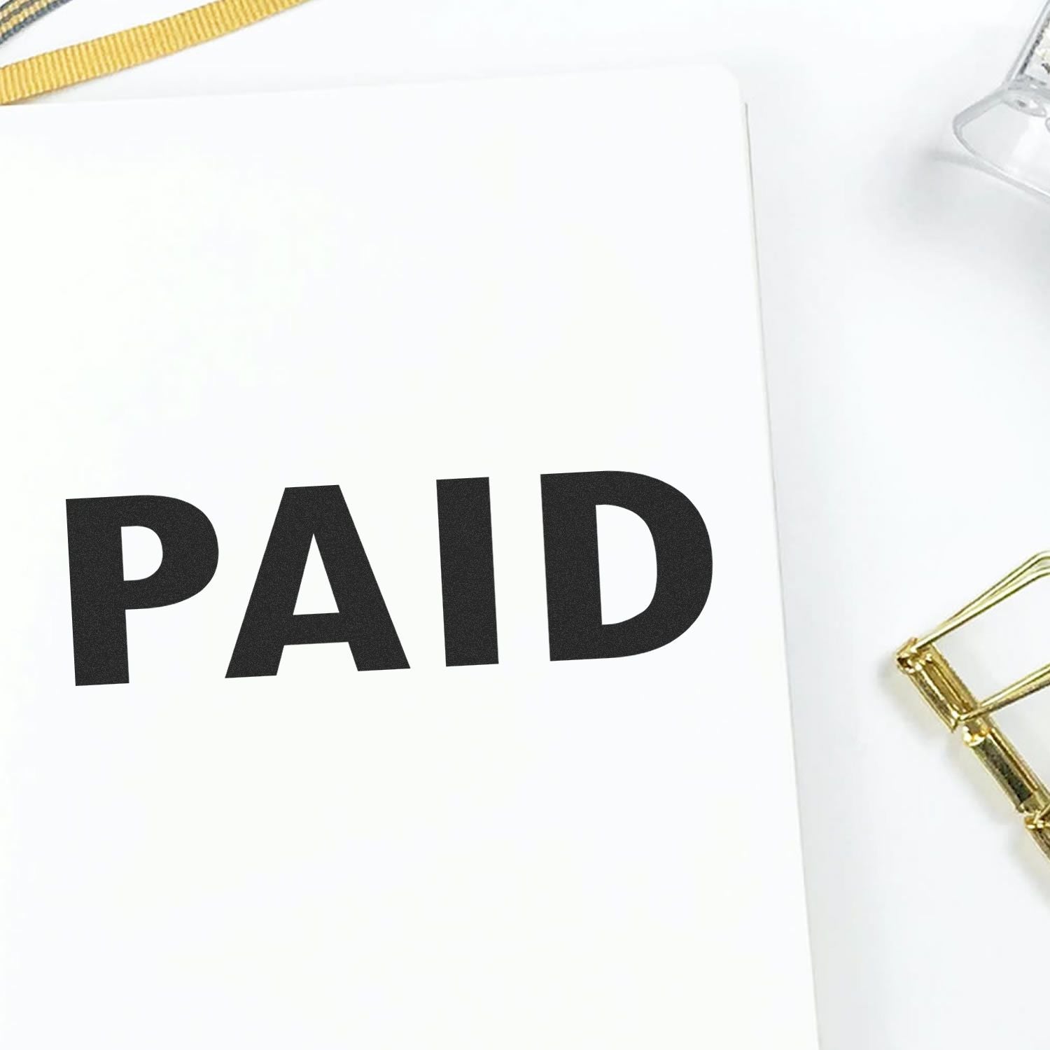 PAID stamp on a white invoice document with a gold chain, indicating payment status and completed transaction.