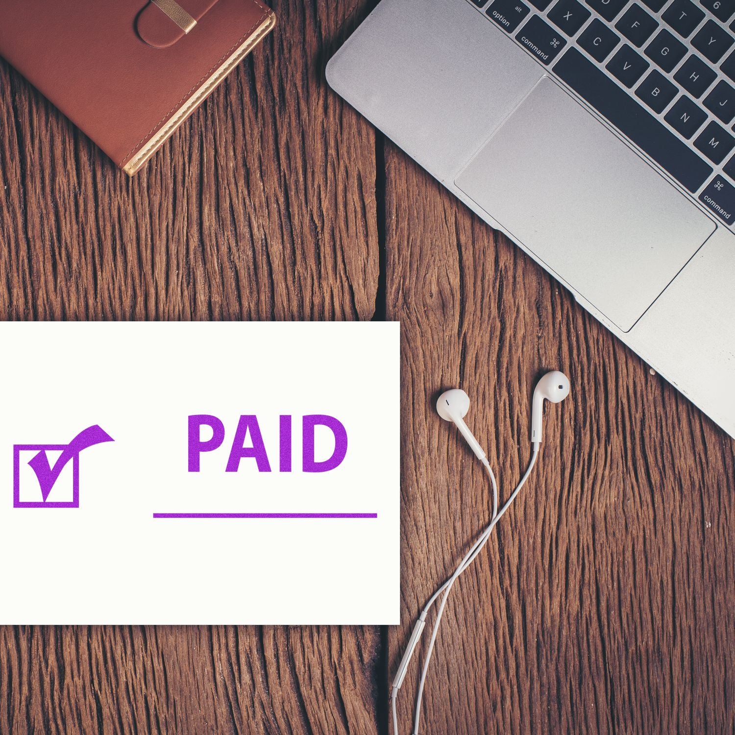 Paid payment status shown on a screen on wooden desk with laptop and earbudsonline transaction confirmation for accounts receivable.