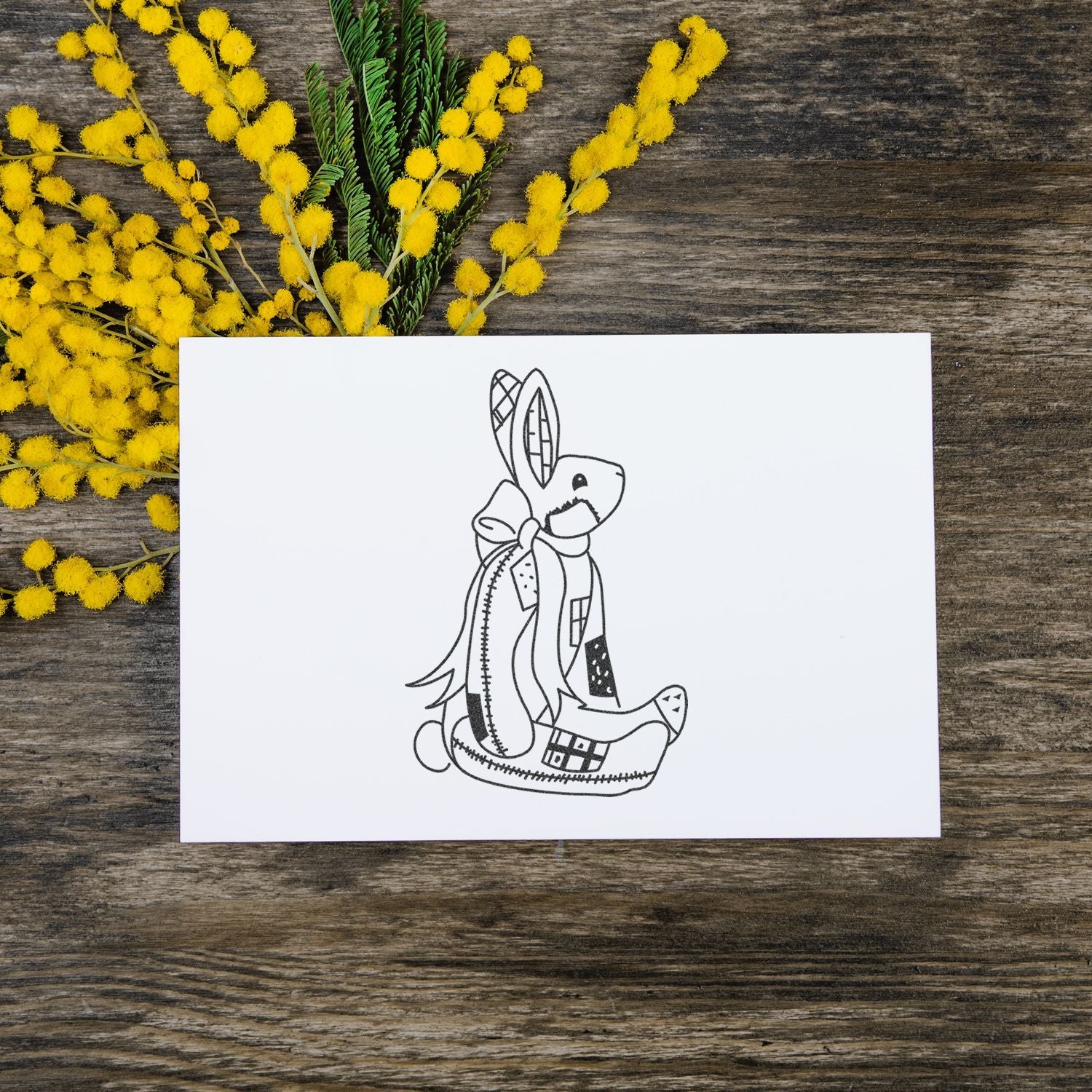 Handmade bunny greeting card on rustic wood background with yellow mimosa flowers