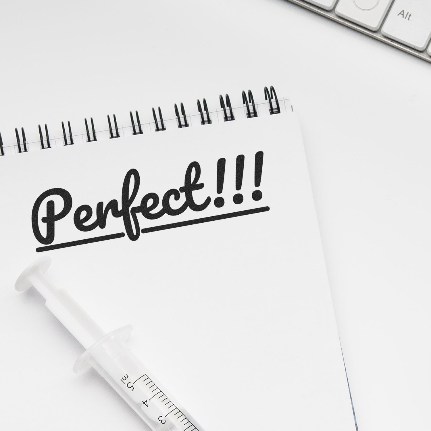 Minimalist white desk flat lay with notebook saying Perfect!!!, pencil, and keyboard on a clean workspace background