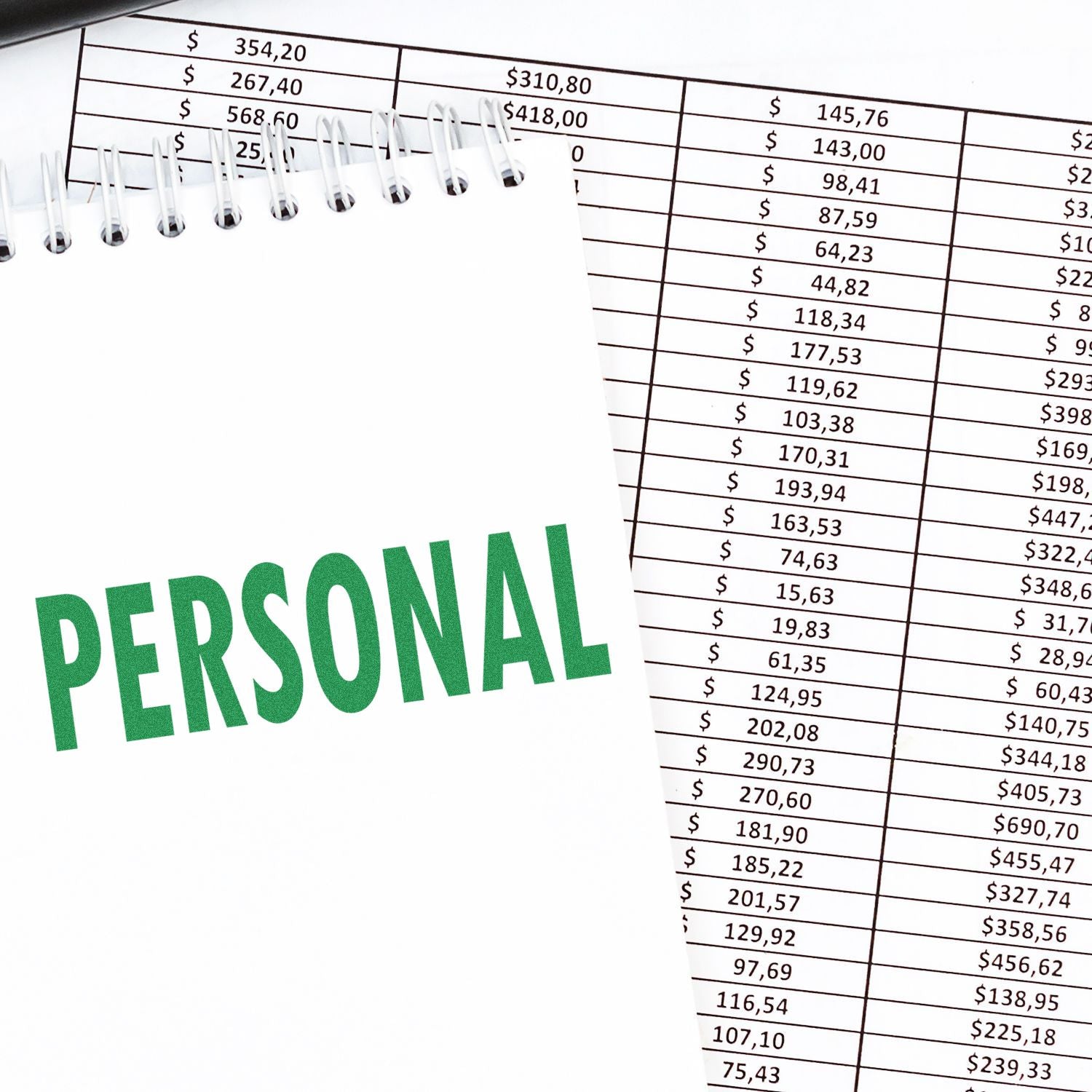 Personal finance notebook on top of an expense spreadsheet with dollar amounts, budgeting and accounting concept.