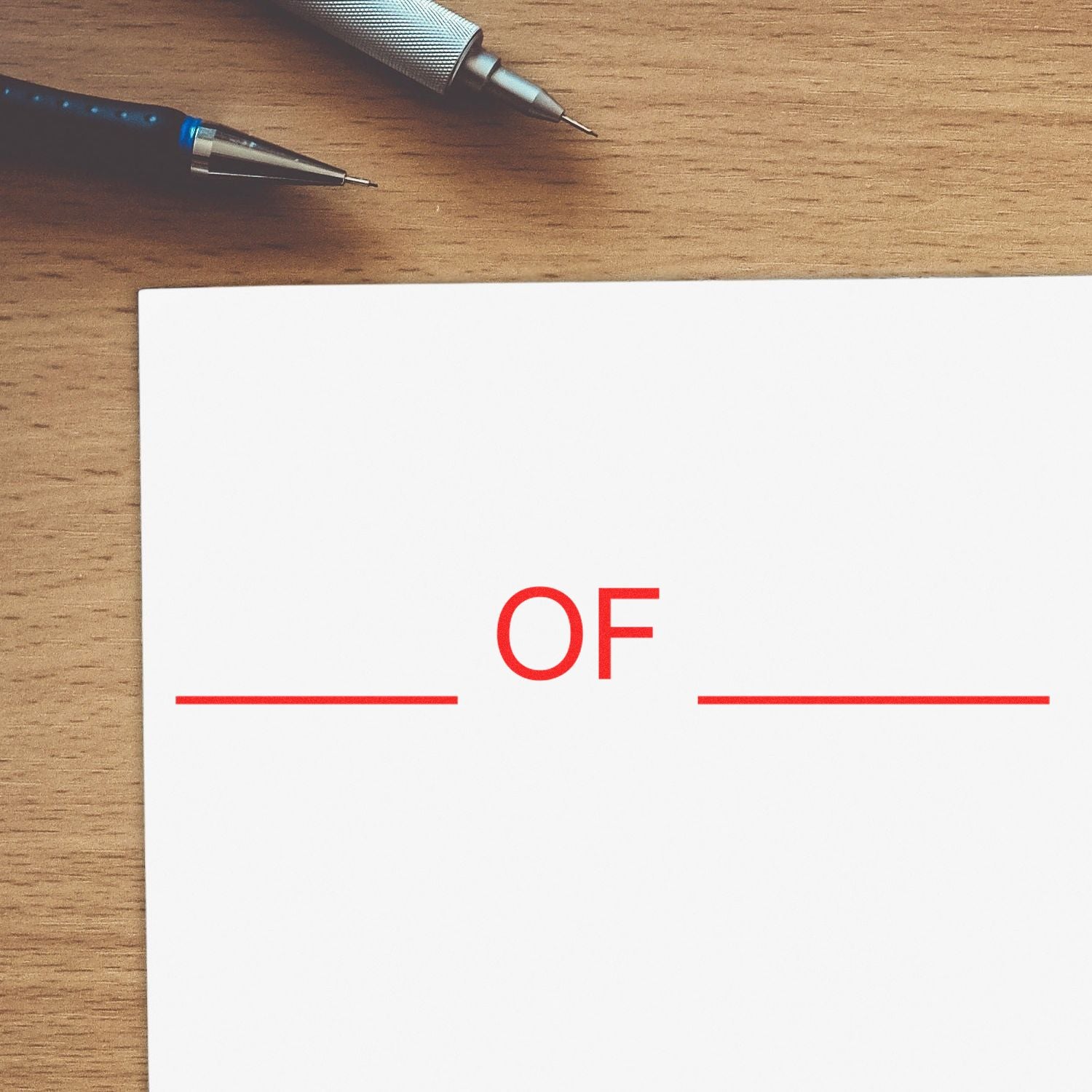 Pens on a wooden desk above a white page with red OF text, representing an office document layout placeholder.