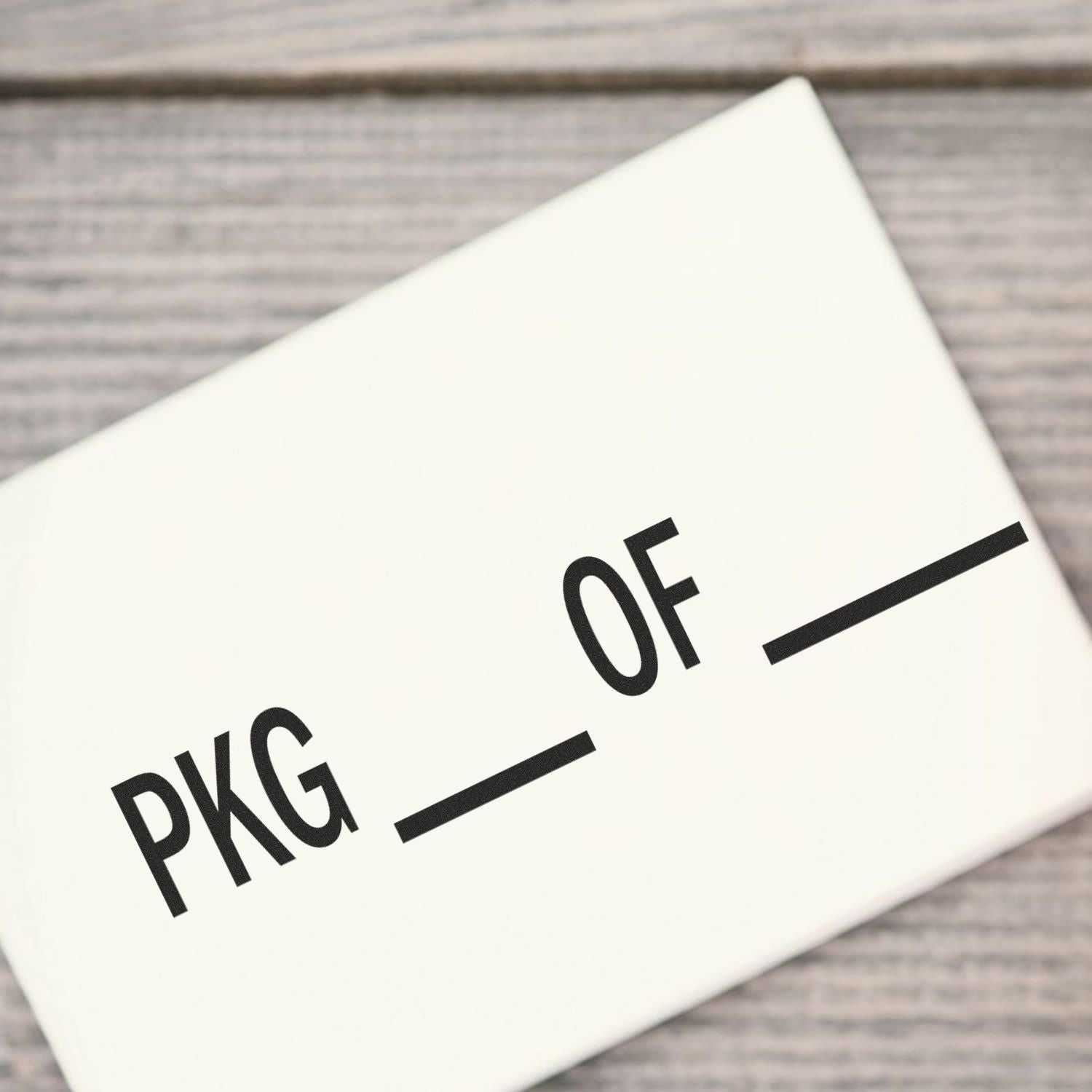 White shipping package box labeled PKG OF on a wooden background, close-up product packaging image
