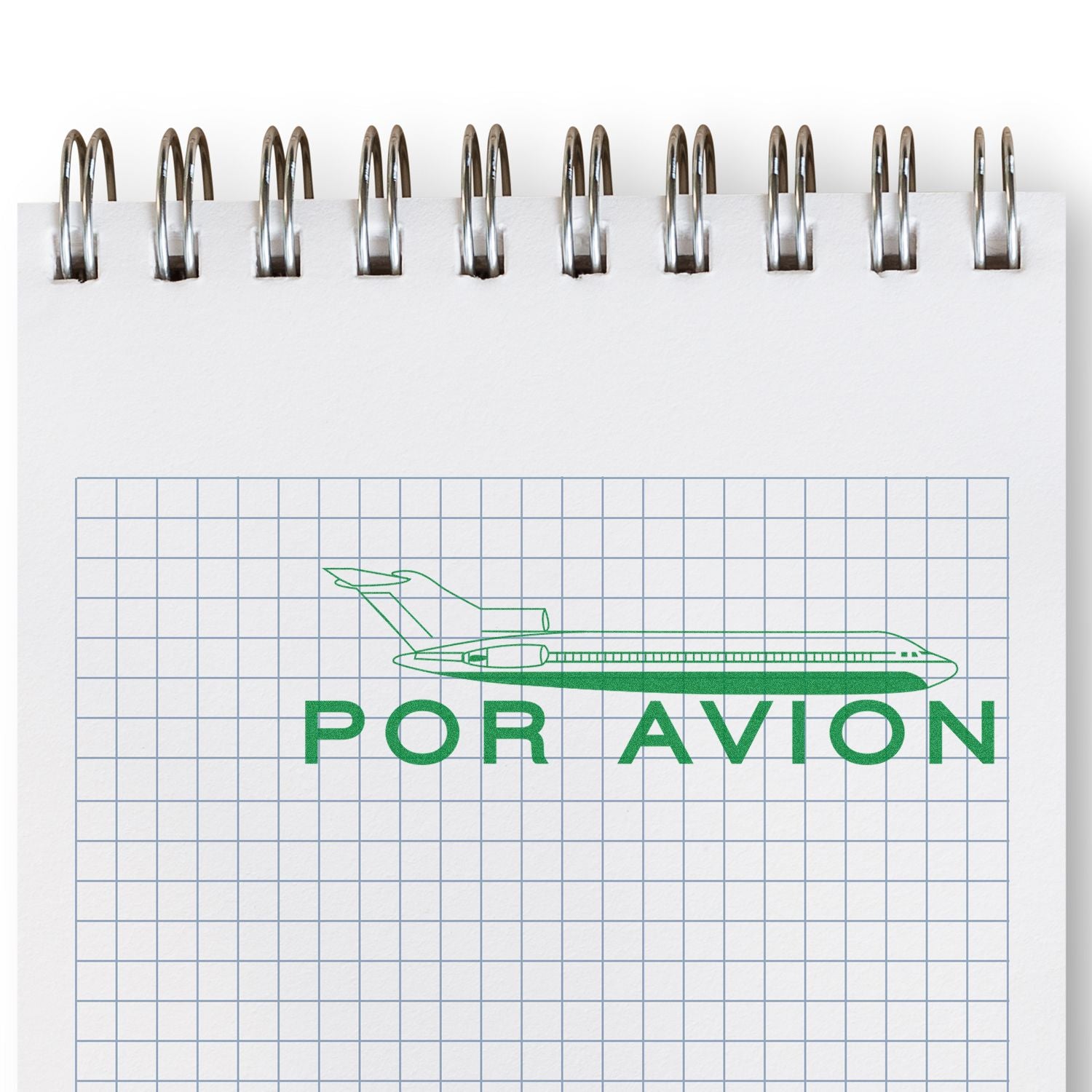 Spiral notebook with graph paper and green Por Avion airplane logo on the cover.
