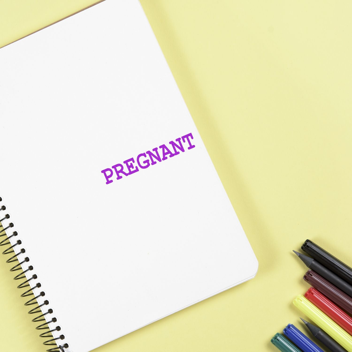 Pregnant pregnancy concept on open notebook with pens, highlighting a maternity announcement message.