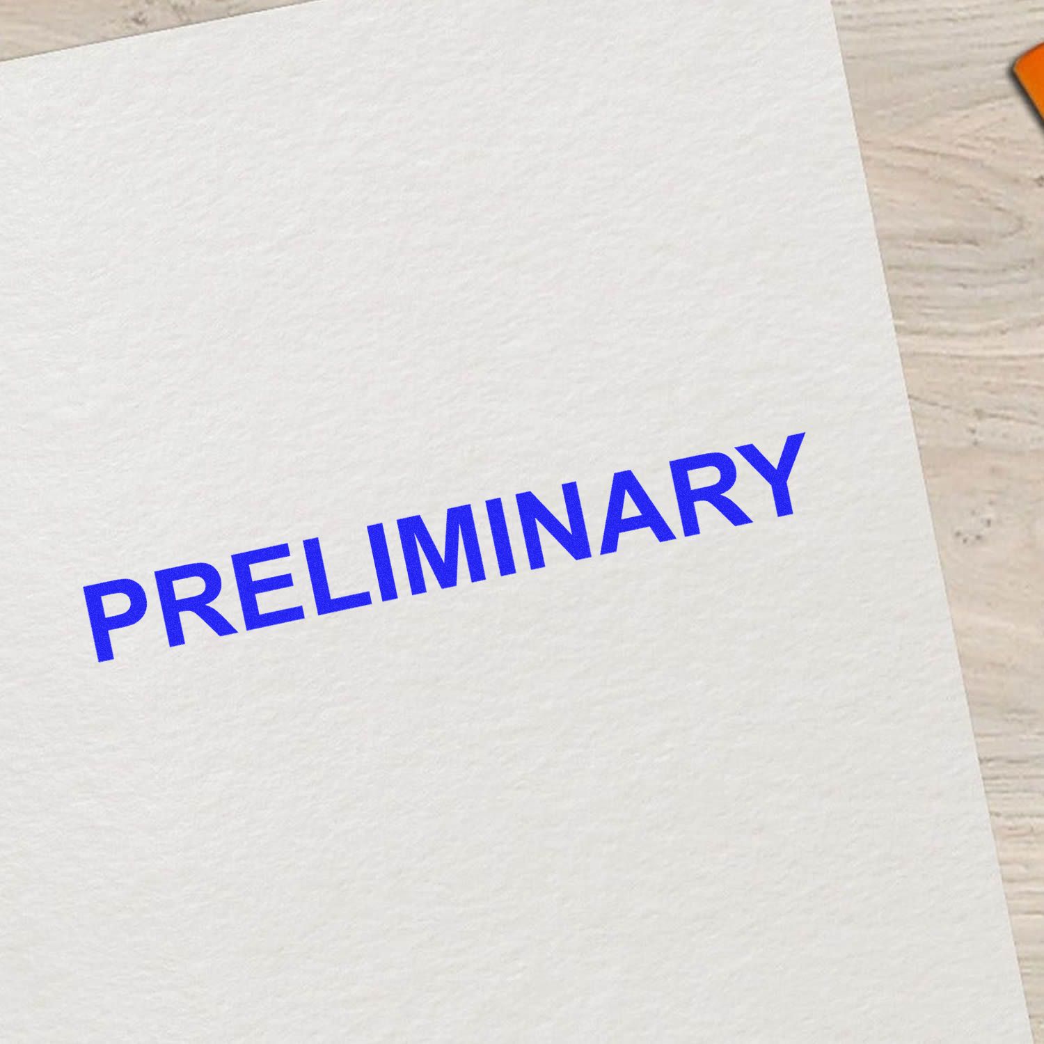 Preliminary document on white paper with bold blue text on a desk.