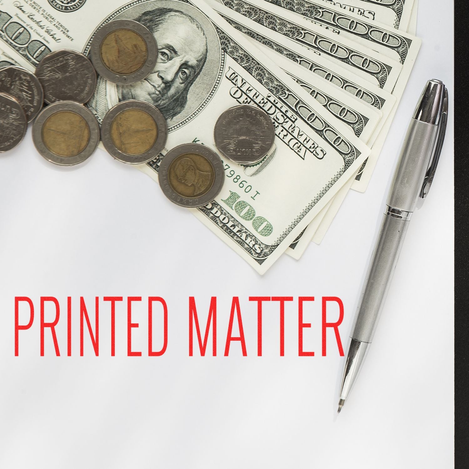 Printed matter concept with U.S. dollar bills, coins, and a silver pen on a white background.