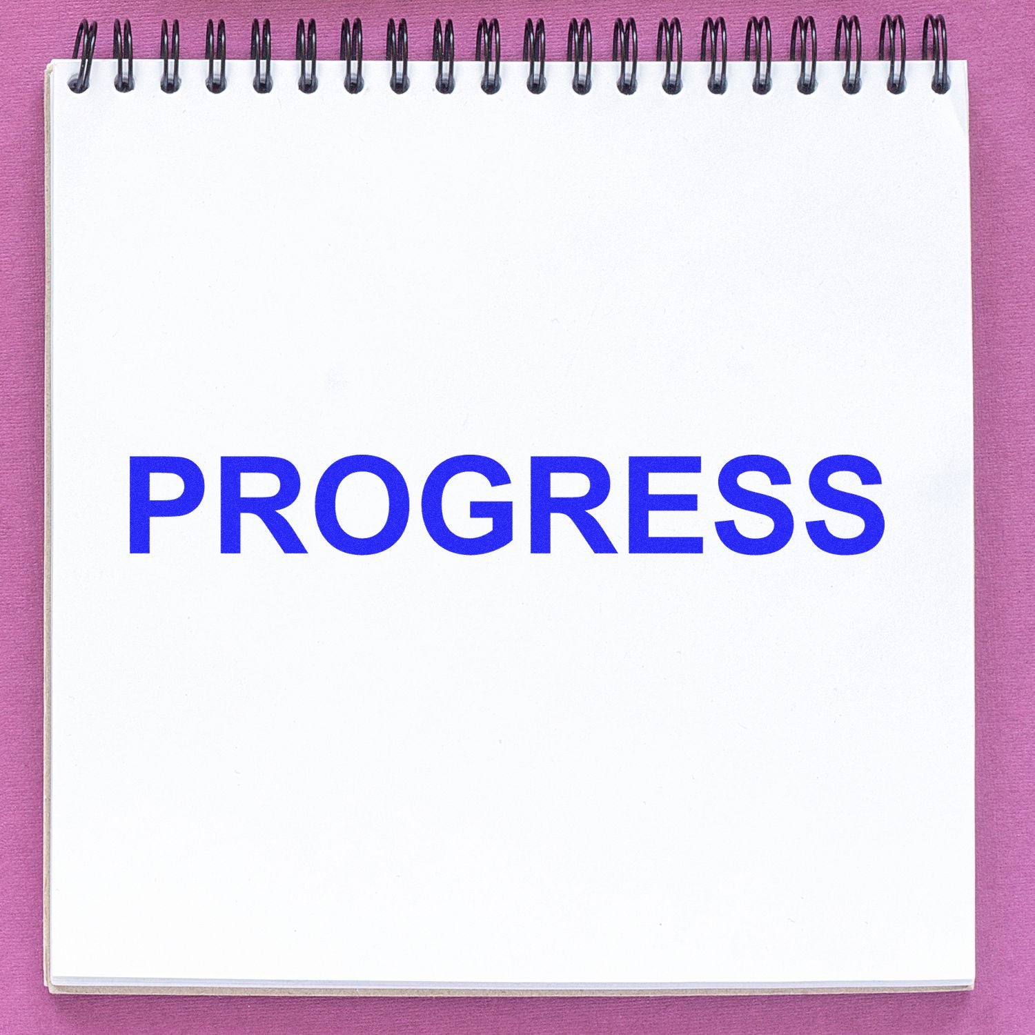 Blank spiral notebook with the word PROGRESS in bold blue letters on a pink background.