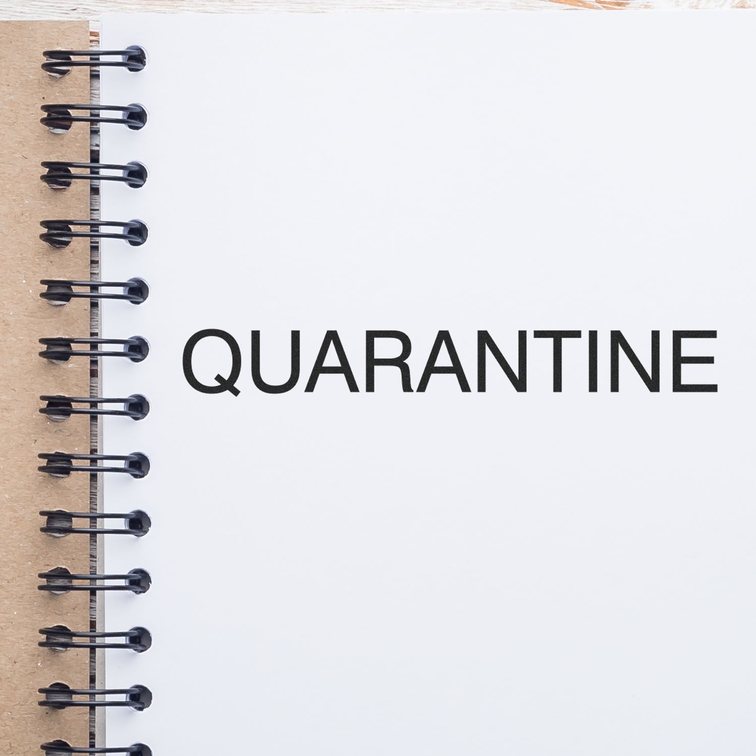 Notepad with the word quarantine on a spiral-bound notebook page, symbolizing self-isolation and public health safety.