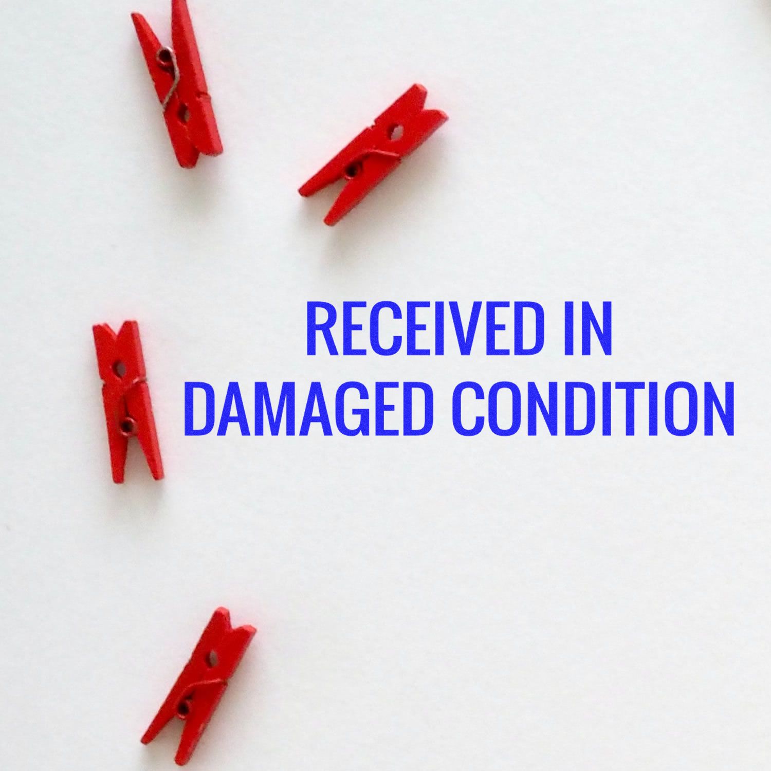 Red clothespins on white background with text Received in Damaged Condition, illustrating shipping damage notice.