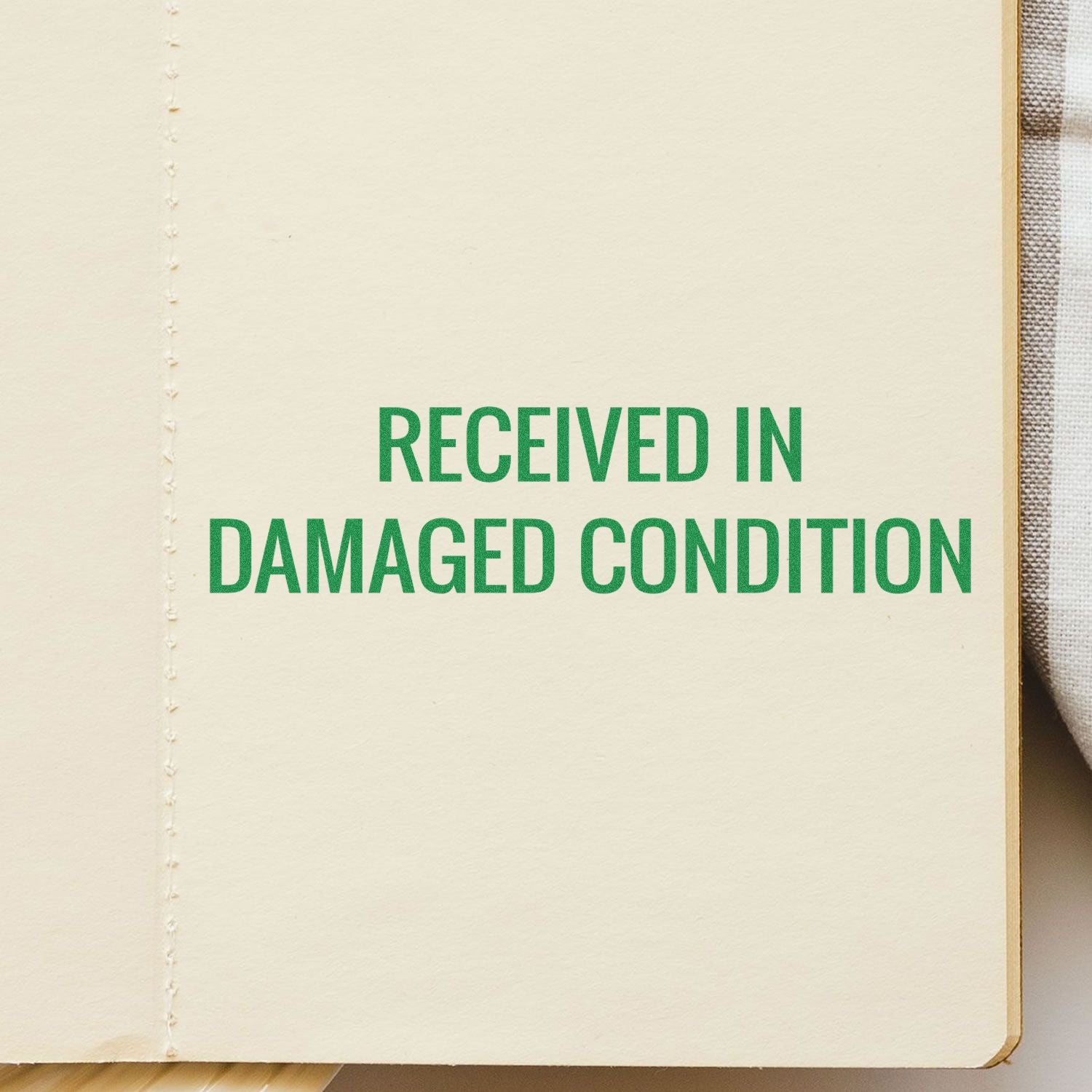 Open notebook page stamped with green text Received in Damaged Condition on a cream background.