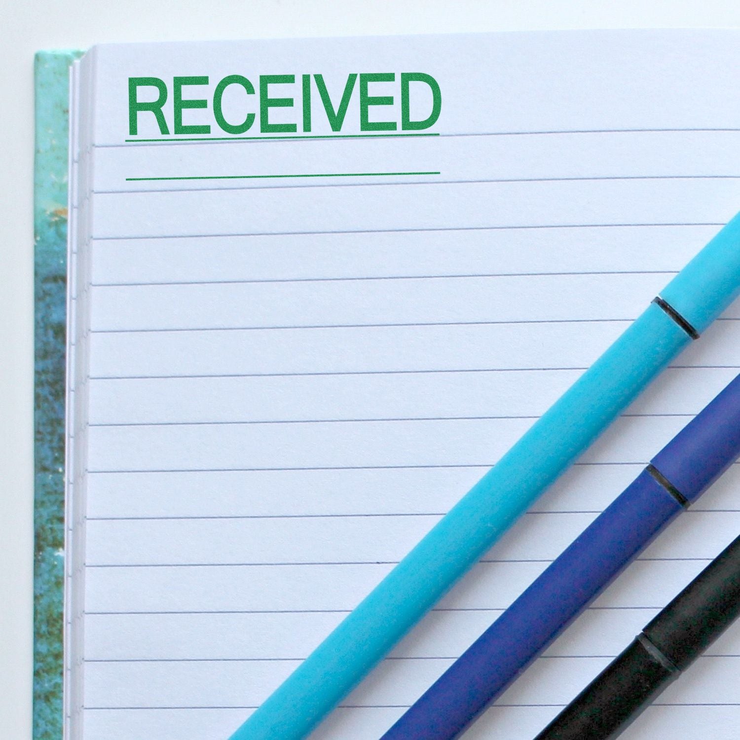 Notebook page showing RECEIVED with blue pens, symbolizing receipt confirmation for incoming documents or messages.