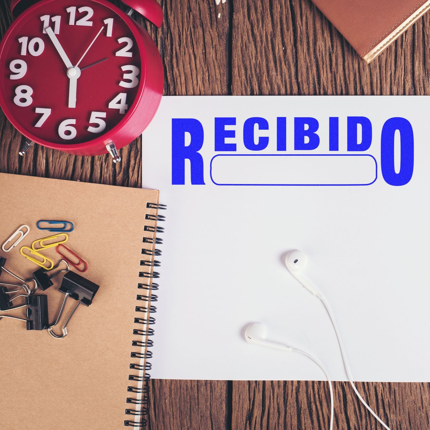 Alarm clock and headphones beside notebook with Recibido text, productivity notification for time management