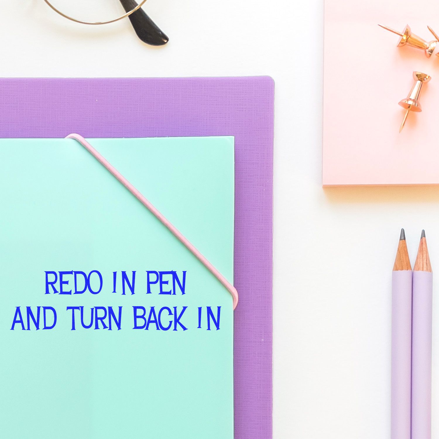 Stationery flat lay with colored paper, pencils and pen for writing the message Redo in pen and turn back in reminder.