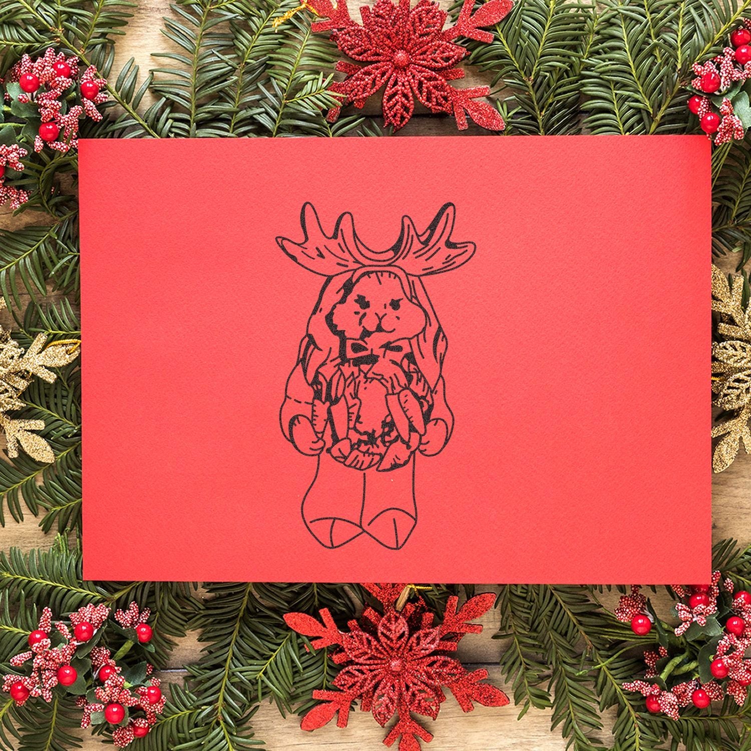 Festive Christmas card with cute moose illustration on red background, framed by holiday greenery and ornaments.