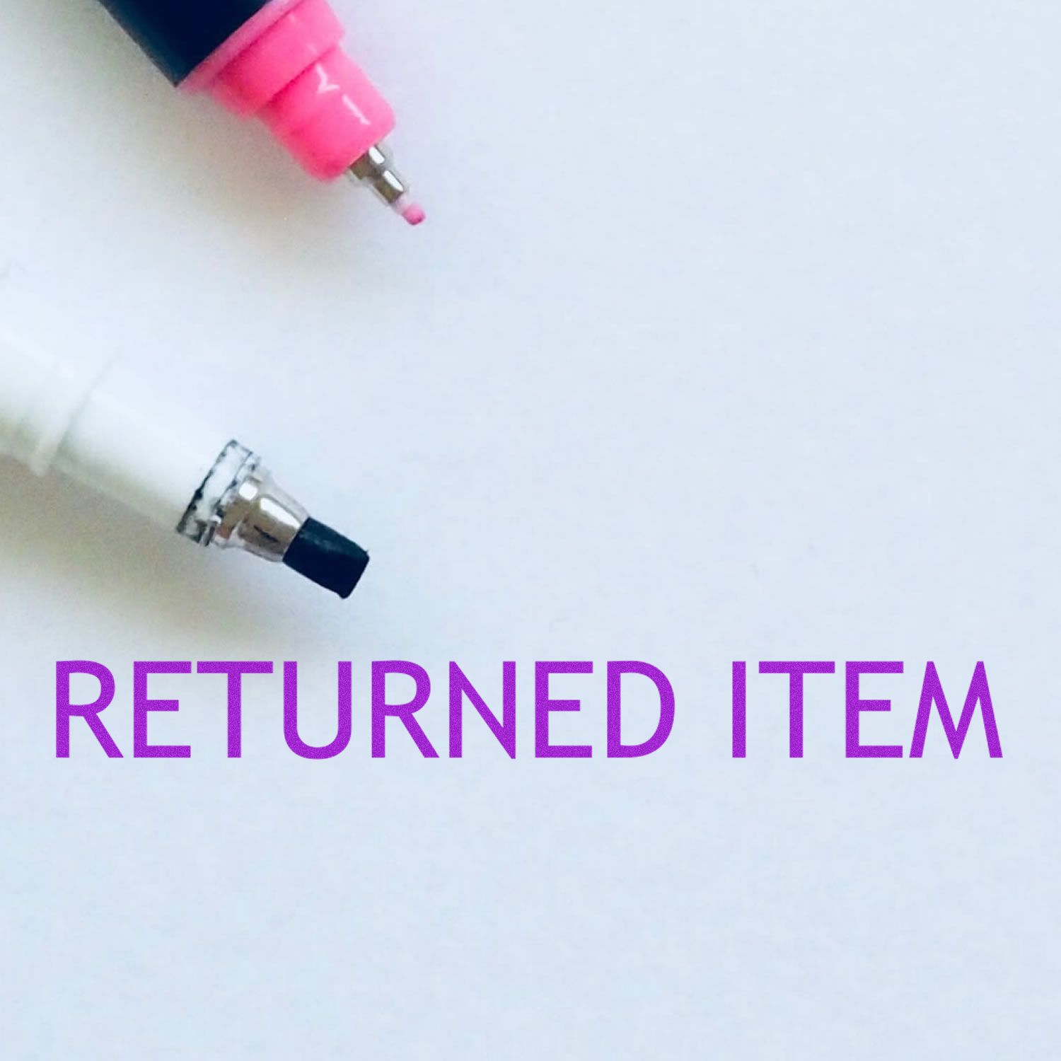 Returned item notice with two pen tips on a white background and purple text reading RETURNED ITEM