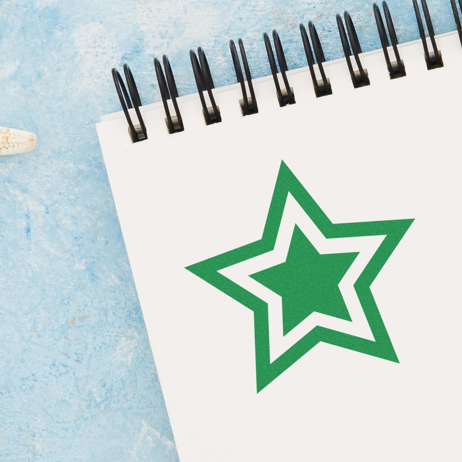 Spiral notebook with green star logo on a blue textured background