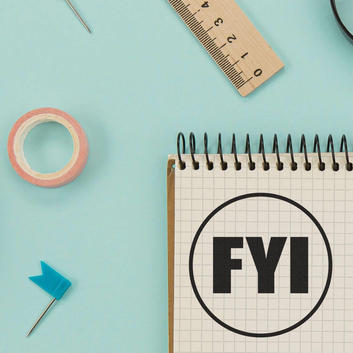 FYI notebook with stationery, ruler, tape, and push pin on a blue background.