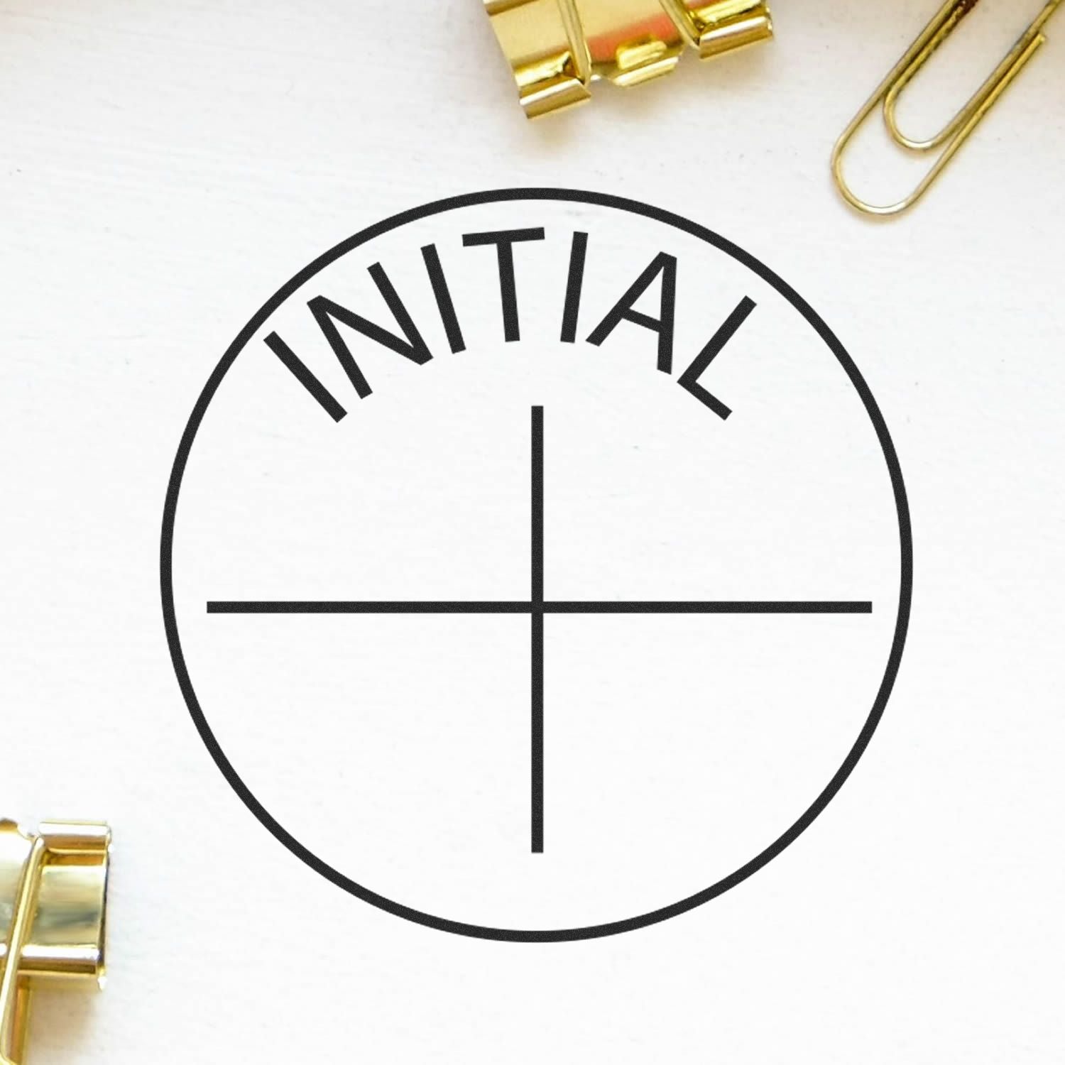 Minimalist INITIAL logo design with circle and cross on a white background, accented by gold paper clips.