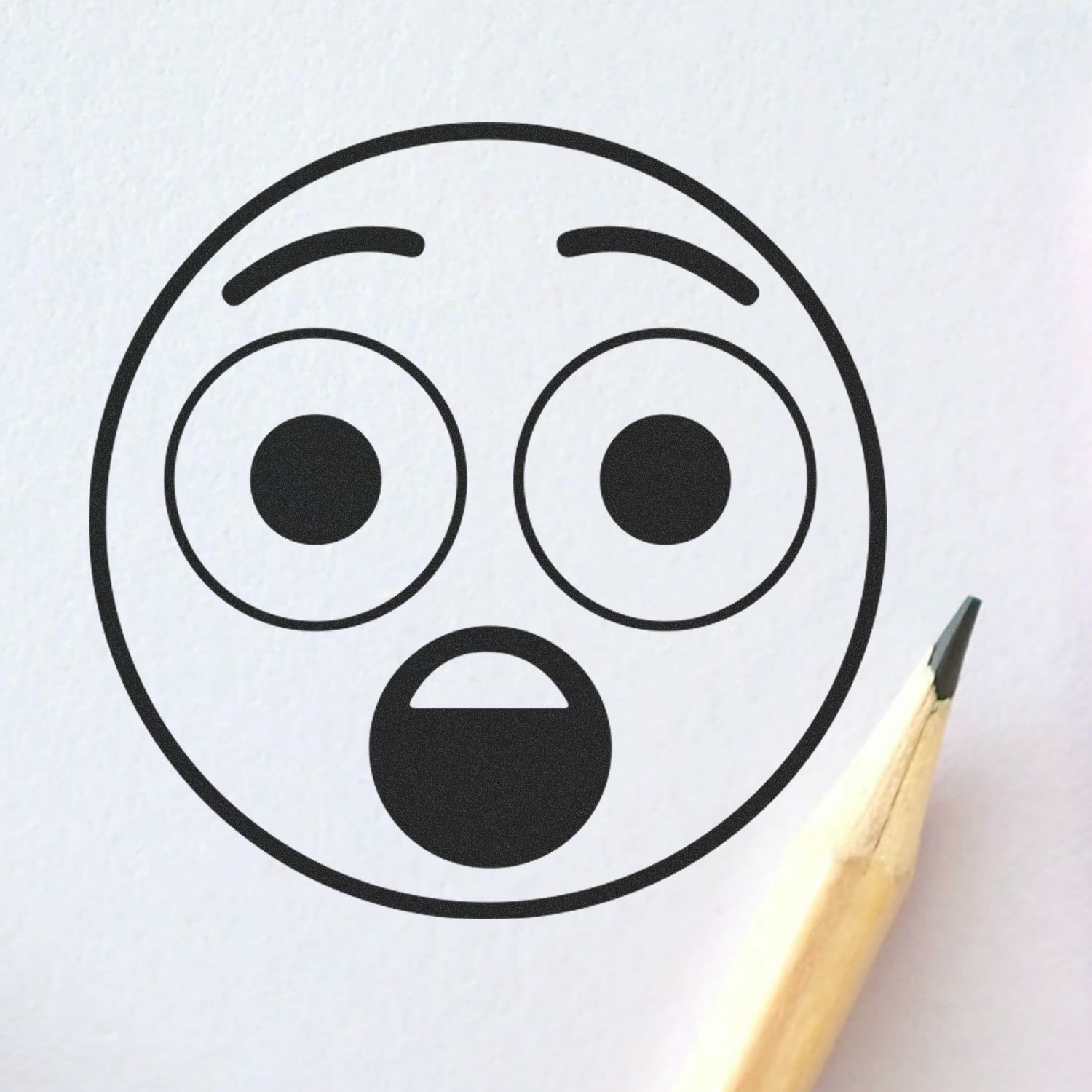 Surprised emoji face drawing on white paper with pencil, simple black outline illustration.