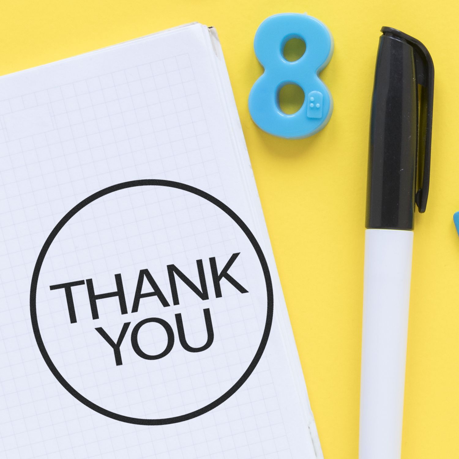 Thank you note on notebook with pen and colorful number 8 on yellow background.