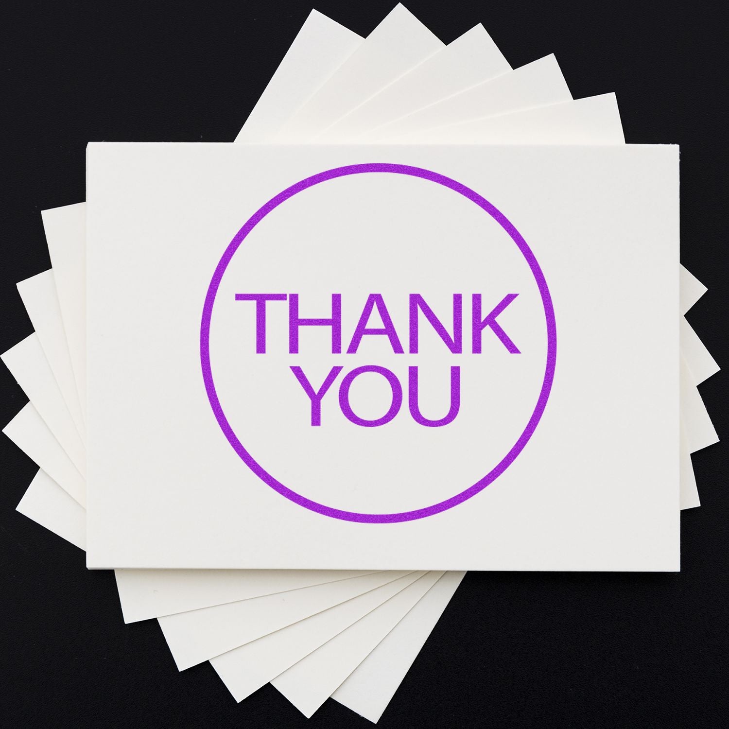 Stack of white thank you cards with purple THANK YOU text on a black background.