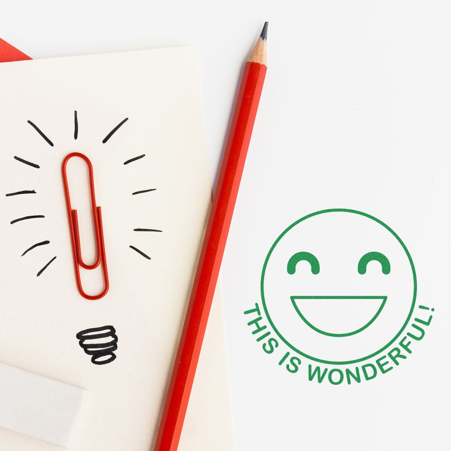 Red pencil with paperclip lightbulb doodle and This is wonderful smiley on white notebook paper, creative stationery concept.